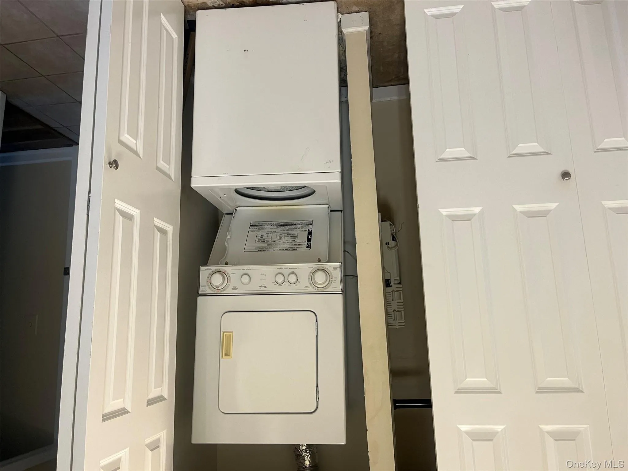 Laundry room with stacked washer / drying machine and tile patterned floors Laundry room with stacked washer / drying machine and tile patterned floors