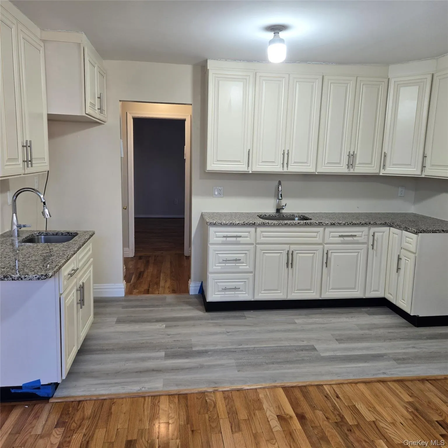 Kitchen featuring dark stone counters, light wood-style floors, and white cabinetry Kitchen featuring dark stone counters, light wood-style floors, and white cabinetry
