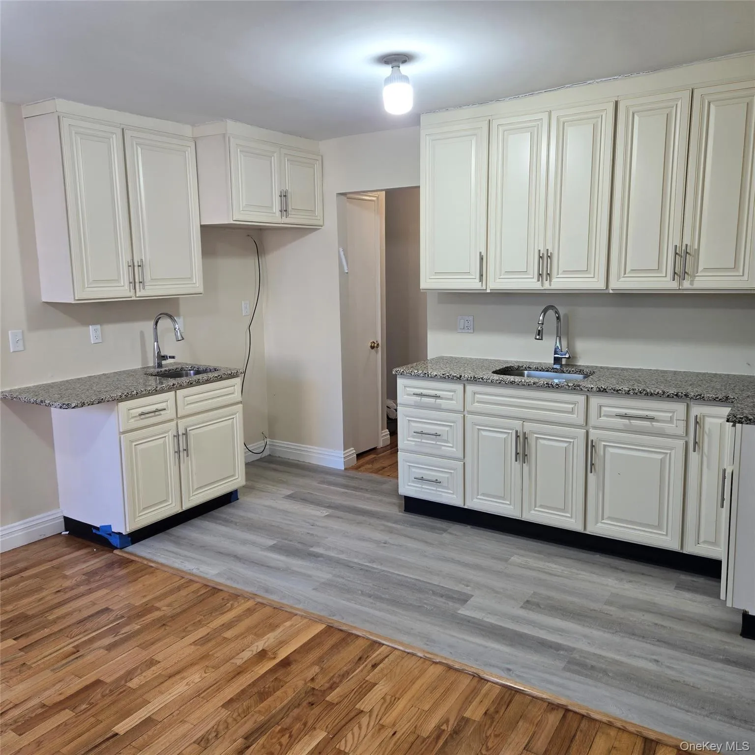 Kitchen featuring light stone counters, light wood finished floors, and white cabinetry Kitchen featuring light stone counters, light wood finished floors, and white cabinetry