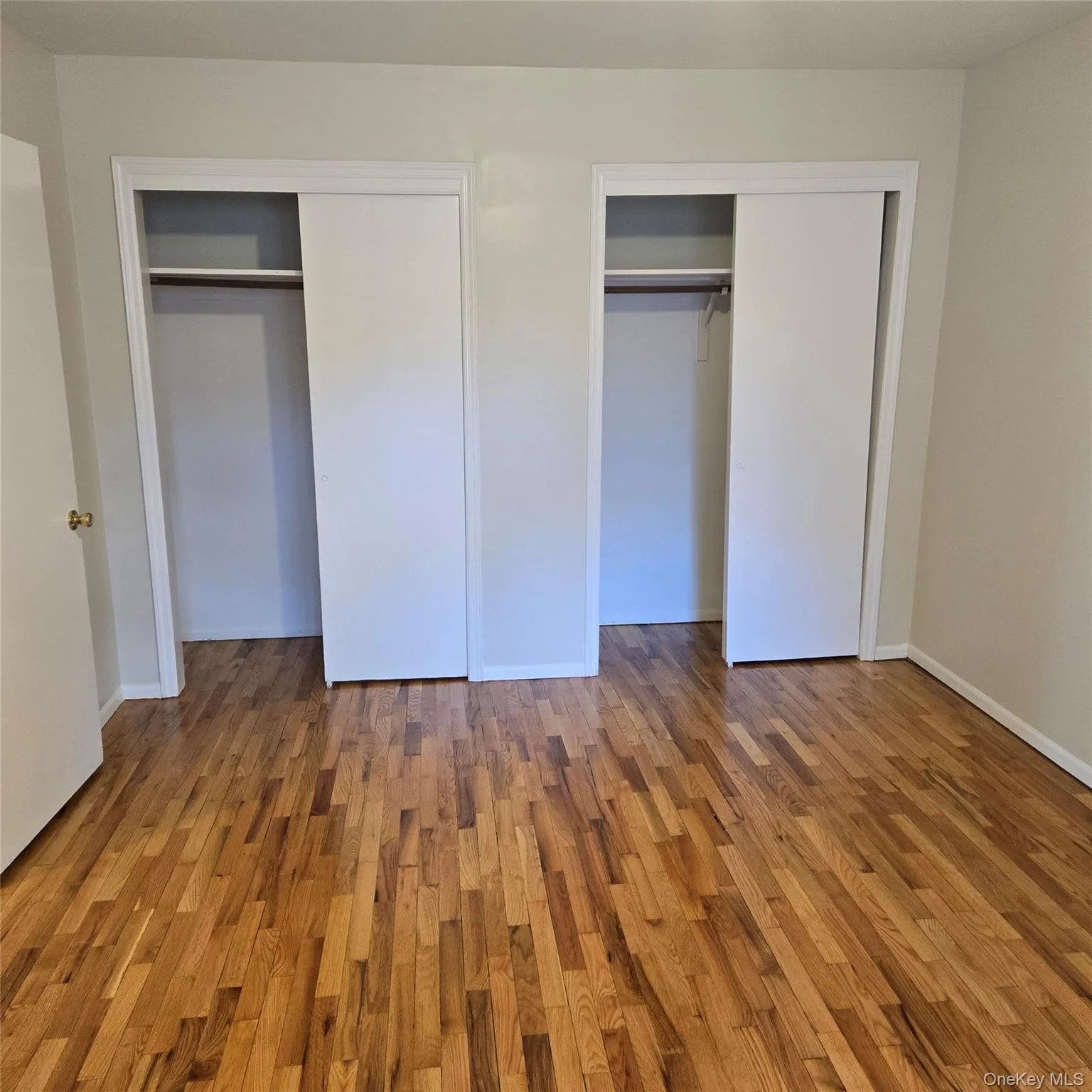 Unfurnished bedroom with multiple closets and wood finished floors Unfurnished bedroom with multiple closets and wood finished floors