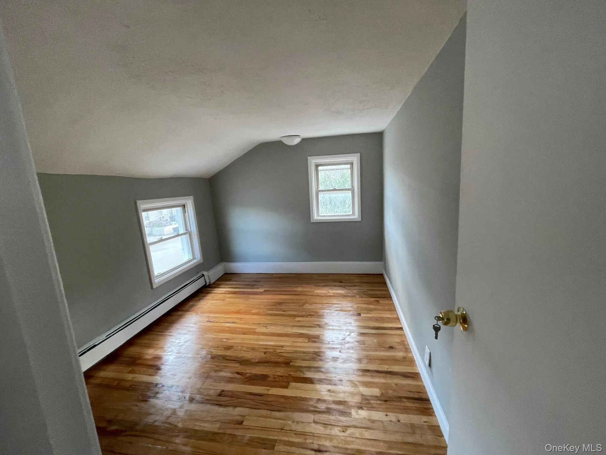 Bonus room with a baseboard radiator, lofted ceiling, and light wood-style flooring Bonus room with a baseboard radiator, lofted ceiling, and light wood-style flooring