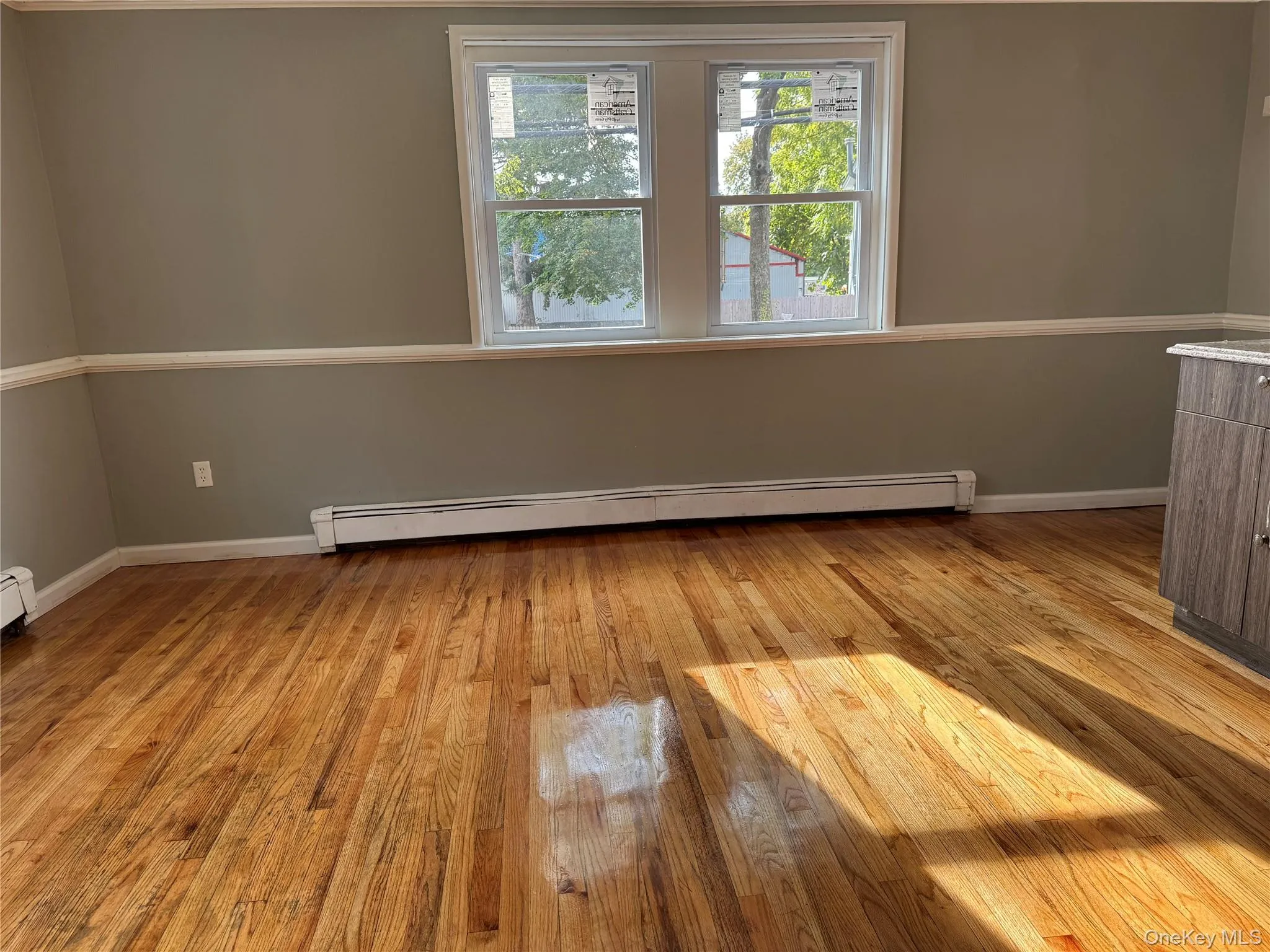 Unfurnished room with light wood-style flooring and a baseboard radiator Unfurnished room with light wood-style flooring and a baseboard radiator