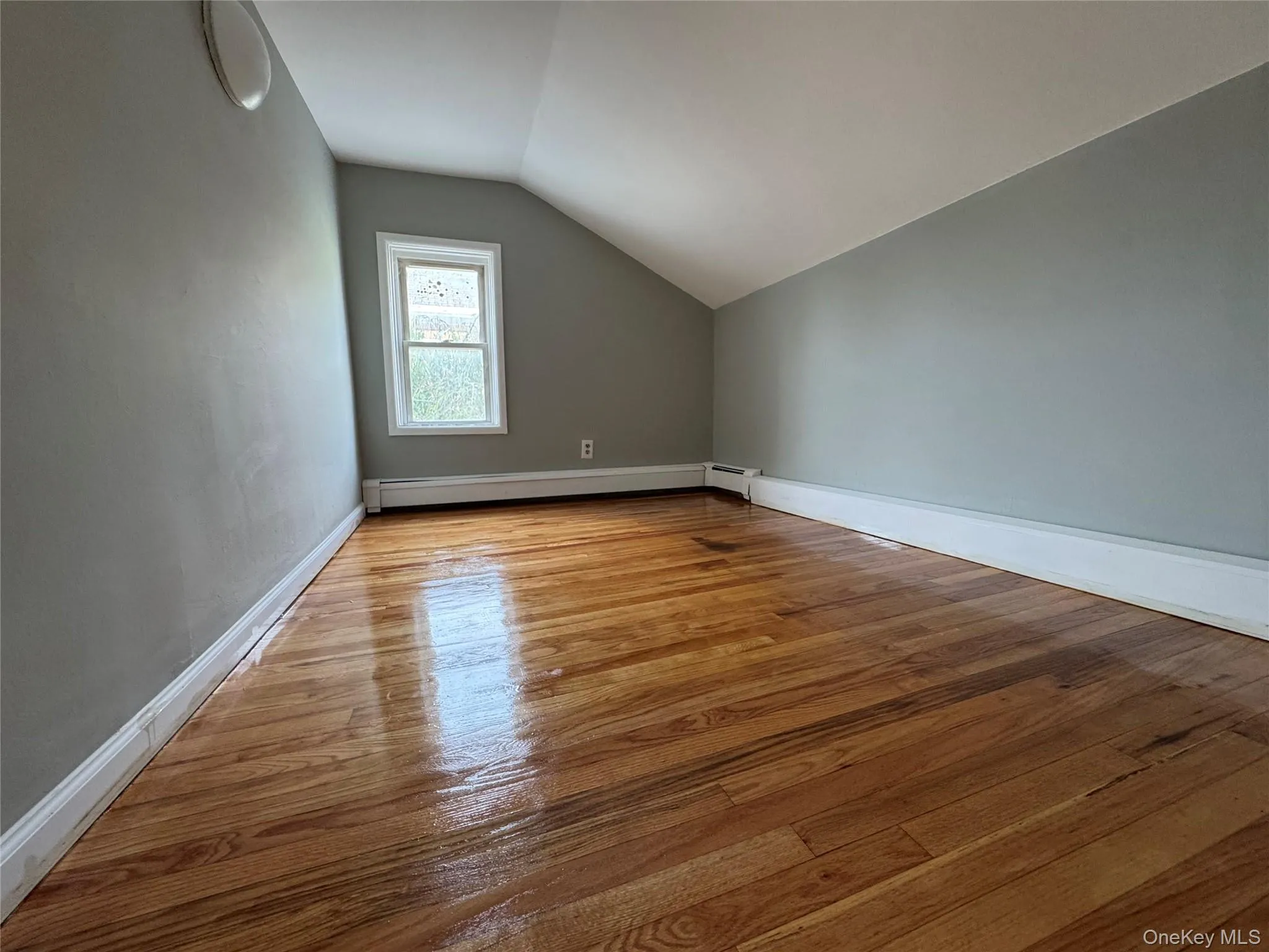 Additional living space with lofted ceiling, light wood-style flooring, and a baseboard radiator Additional living space with lofted ceiling, light wood-style flooring, and a baseboard radiator