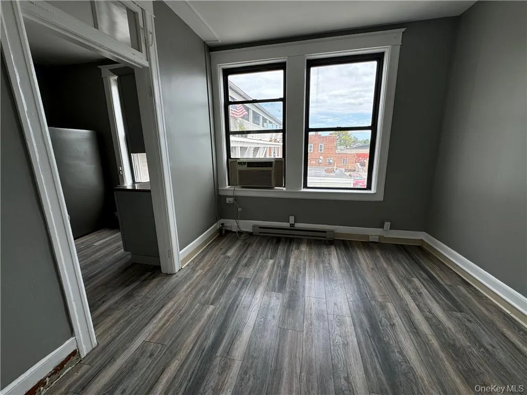 Unfurnished room with cooling unit, a baseboard radiator, and dark hardwood / wood-style flooring Unfurnished room with cooling unit, a baseboard radiator, and dark hardwood / wood-style flooring
