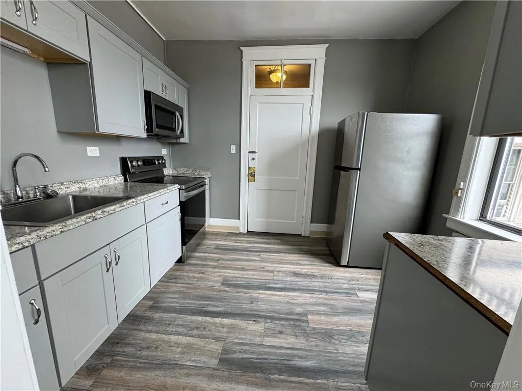 Kitchen featuring white cabinetry, sink, appliances with stainless steel finishes, and hardwood / wood-style flooring Kitchen featuring white cabinetry, sink, appliances with stainless steel finishes, and hardwood / wood-style flooring