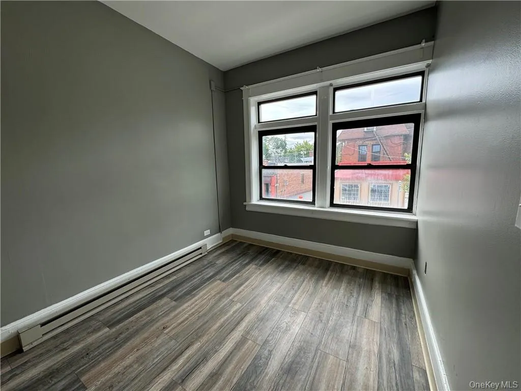 Empty room featuring a baseboard heating unit and wood-type flooring Empty room featuring a baseboard heating unit and wood-type flooring