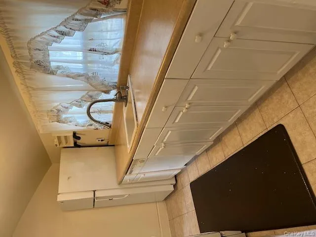 Kitchen with light tile patterned flooring, white cabinets, light countertops, lofted ceiling, and dishwashing machine Kitchen with light tile patterned flooring, white cabinets, light countertops, lofted ceiling, and dishwashing machine