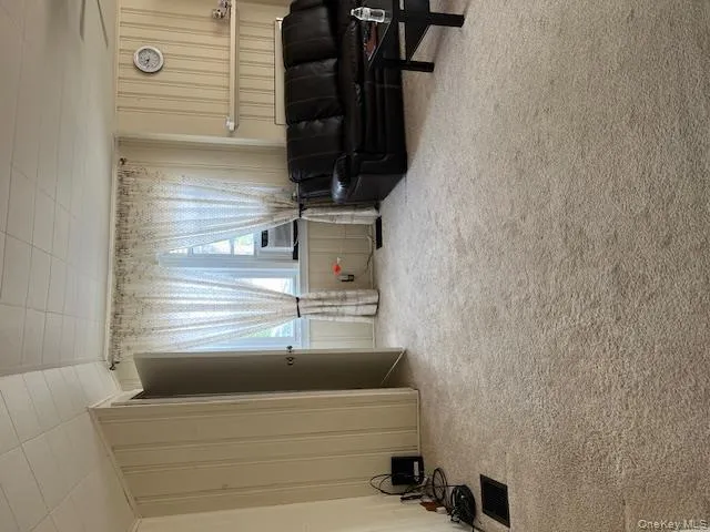 Living room with light carpet, wooden walls, and a decorative wall Living room with light carpet, wooden walls, and a decorative wall