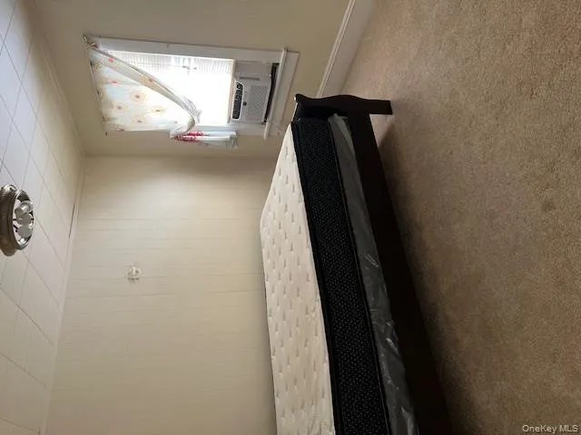 Bedroom with carpet, wooden walls, and cooling unit Bedroom with carpet, wooden walls, and cooling unit