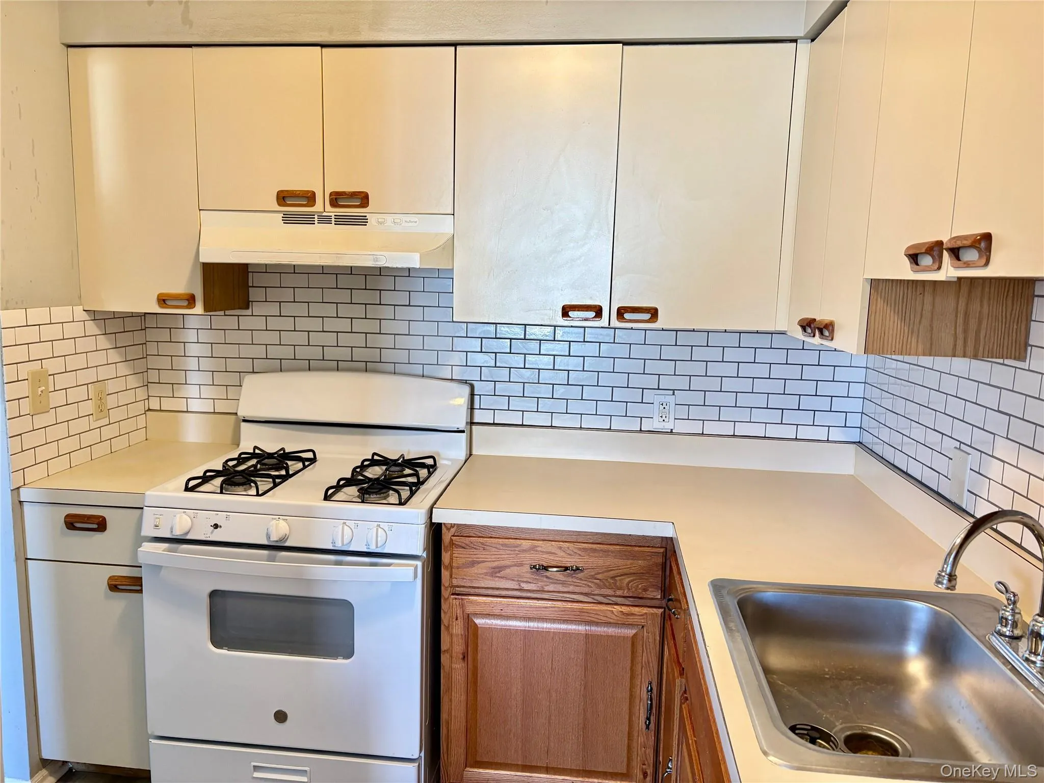 Kitchen with gas range gas stove, decorative backsplash, light countertops, under cabinet range hood Kitchen with gas range gas stove, decorative backsplash, light countertops, under cabinet range hood
