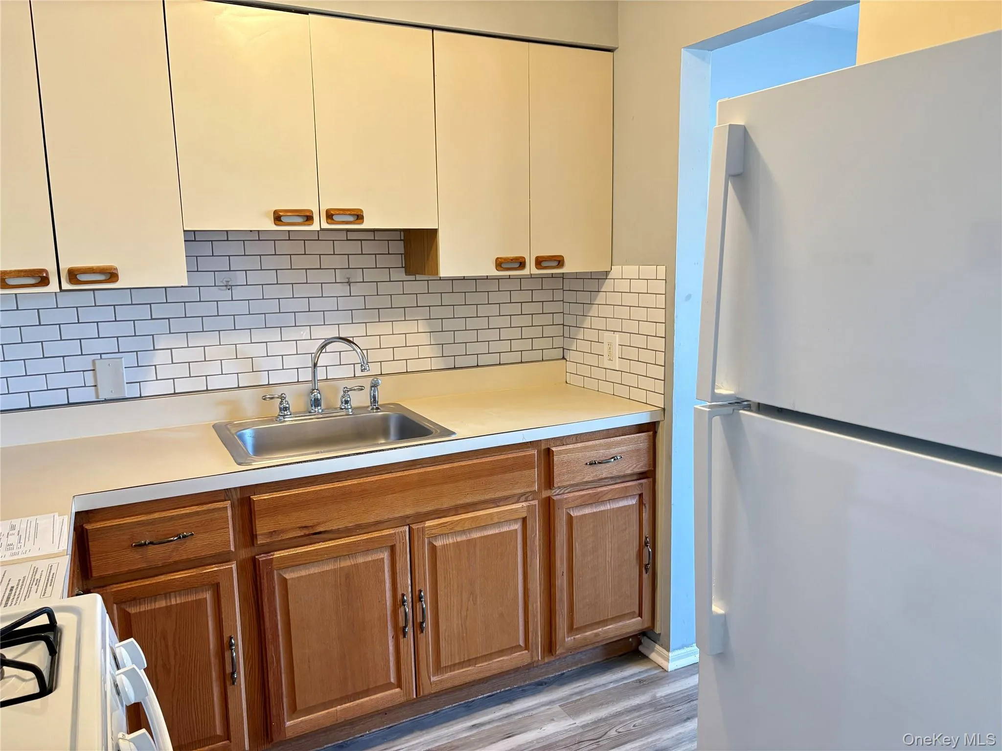 Kitchen featuring white appliances, light countertops, decorative backsplash, light wood-type flooring Kitchen featuring white appliances, light countertops, decorative backsplash, light wood-type flooring