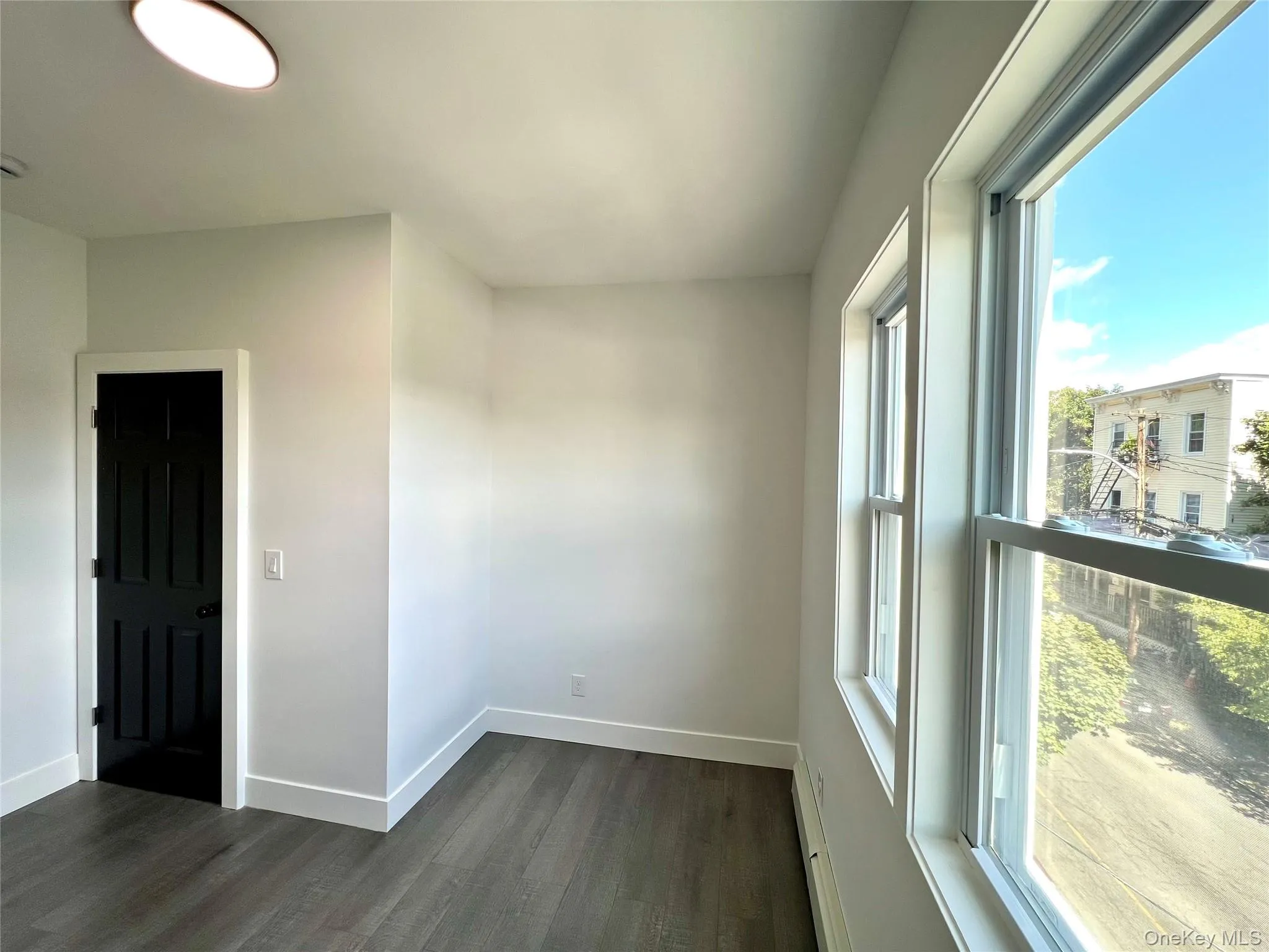 Empty room featuring dark wood-type flooring and baseboard heating Empty room featuring dark wood-type flooring and baseboard heating
