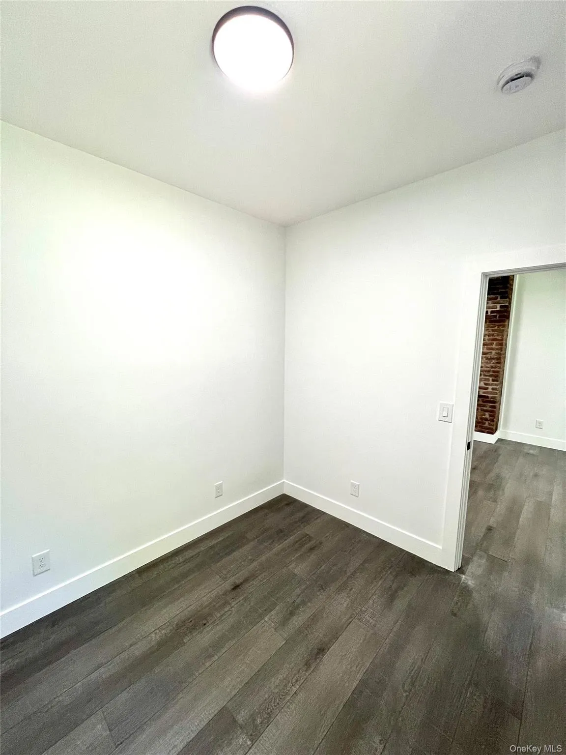 Spare room with baseboards and dark wood-style flooring Spare room with baseboards and dark wood-style flooring