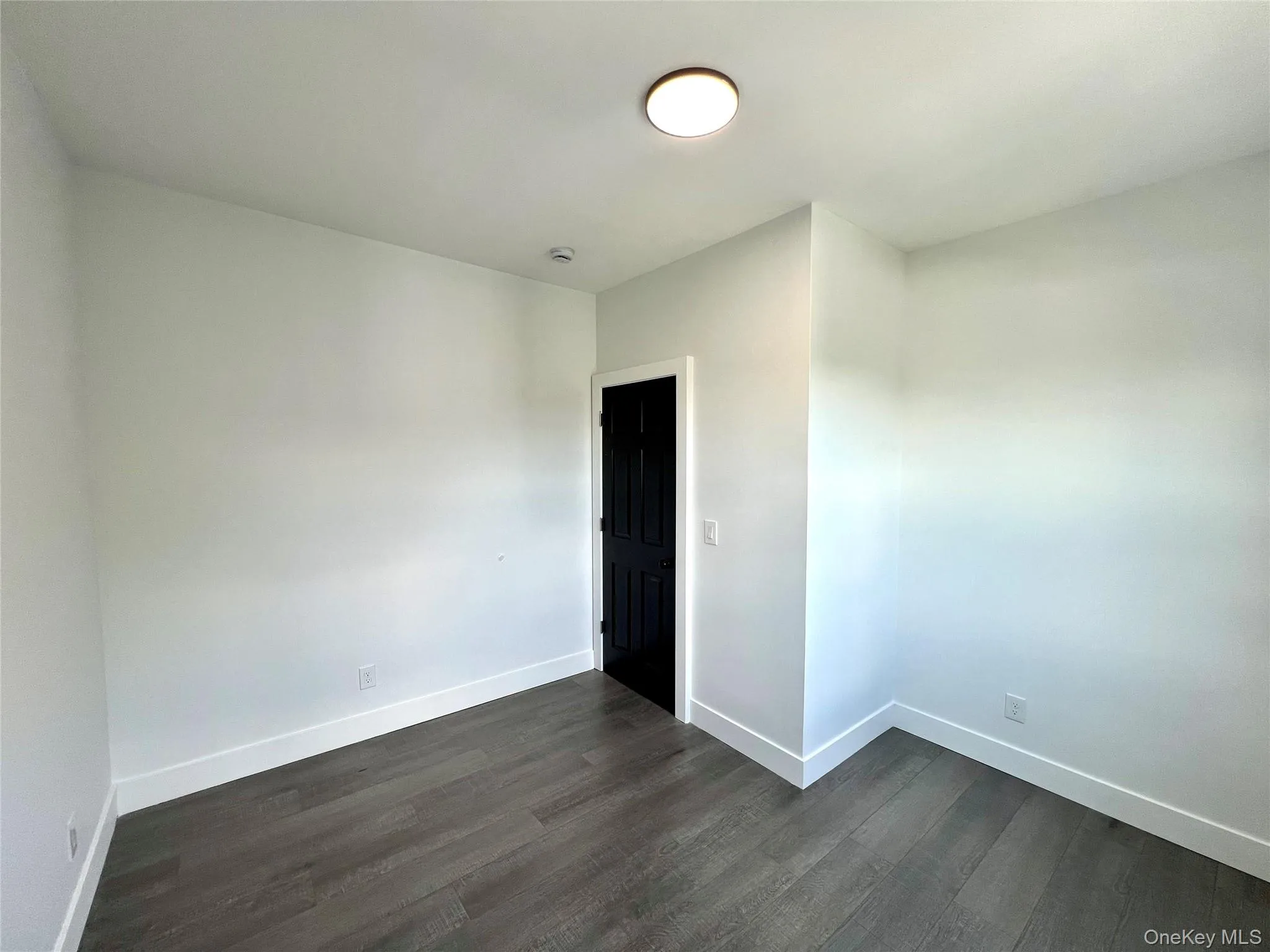Empty room featuring dark wood finished floors and baseboards Empty room featuring dark wood finished floors and baseboards