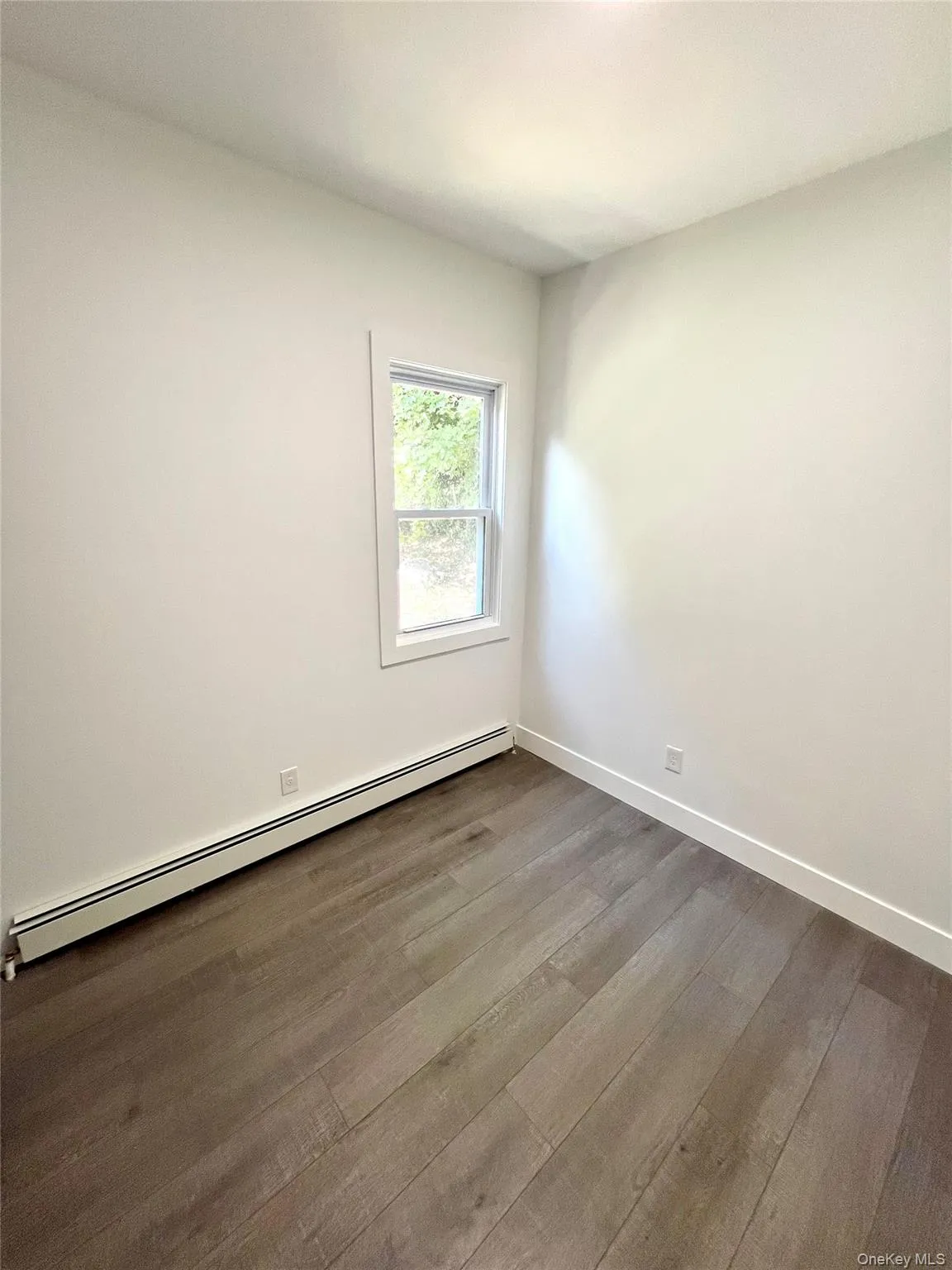 Empty room featuring a baseboard radiator and dark wood-type flooring Empty room featuring a baseboard radiator and dark wood-type flooring