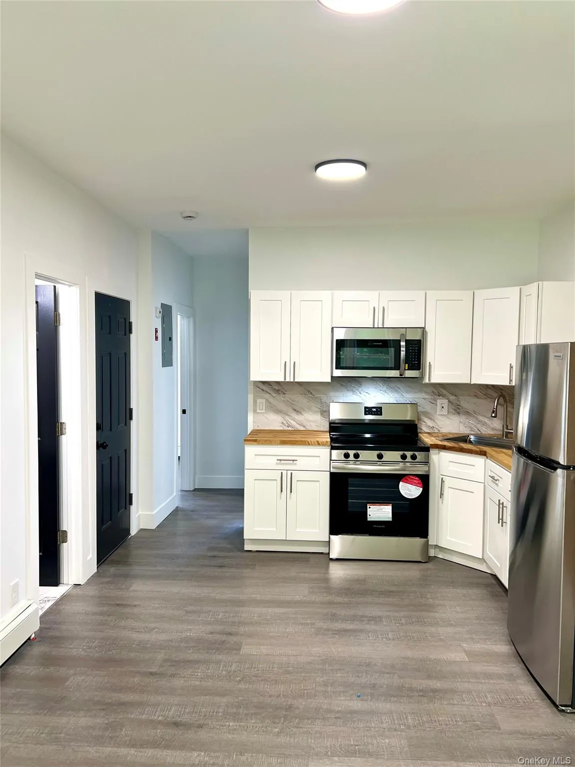 Kitchen featuring wood counters, tasteful backsplash, appliances with stainless steel finishes, and white cabinetry Kitchen featuring wood counters, tasteful backsplash, appliances with stainless steel finishes, and white cabinetry