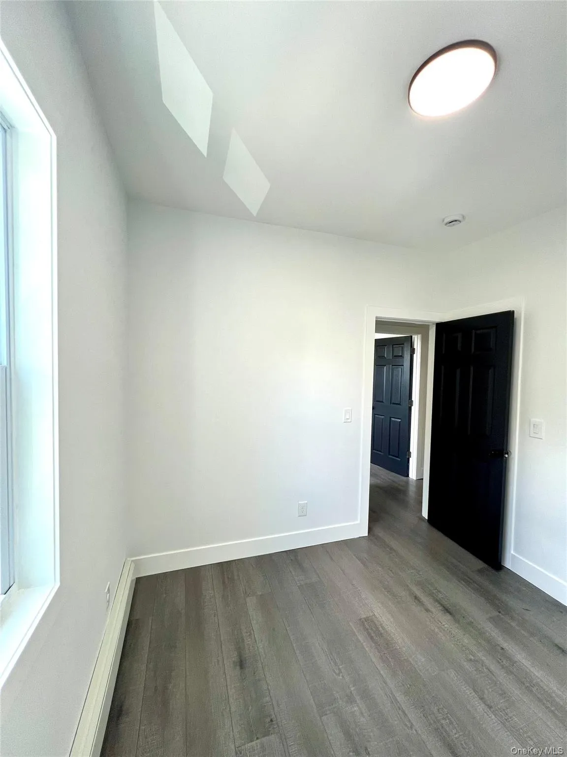 Unfurnished bedroom with wood finished floors, a skylight, and a baseboard radiator Unfurnished bedroom with wood finished floors, a skylight, and a baseboard radiator