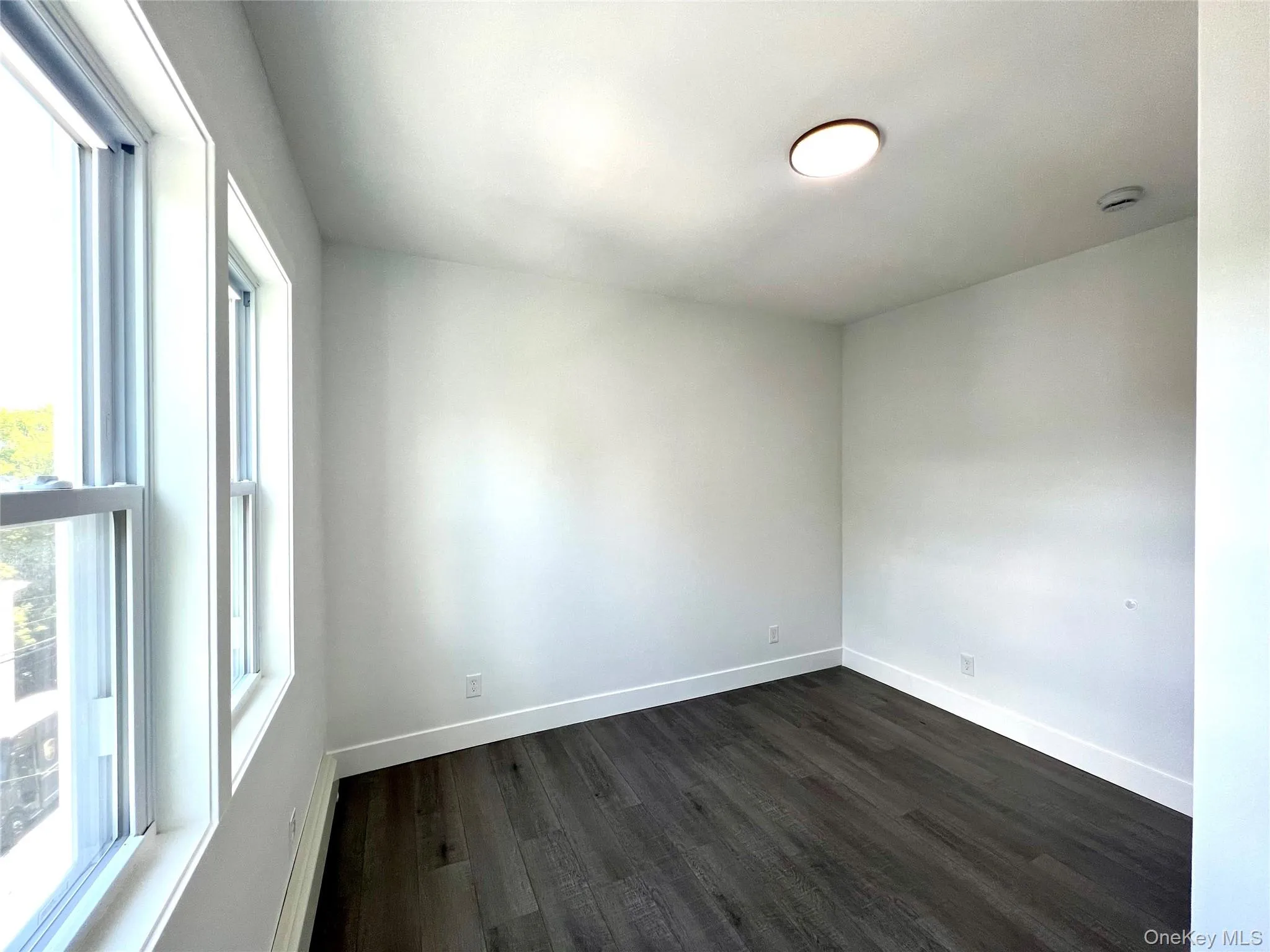 Empty room featuring dark wood-style floors and a baseboard heating unit Empty room featuring dark wood-style floors and a baseboard heating unit