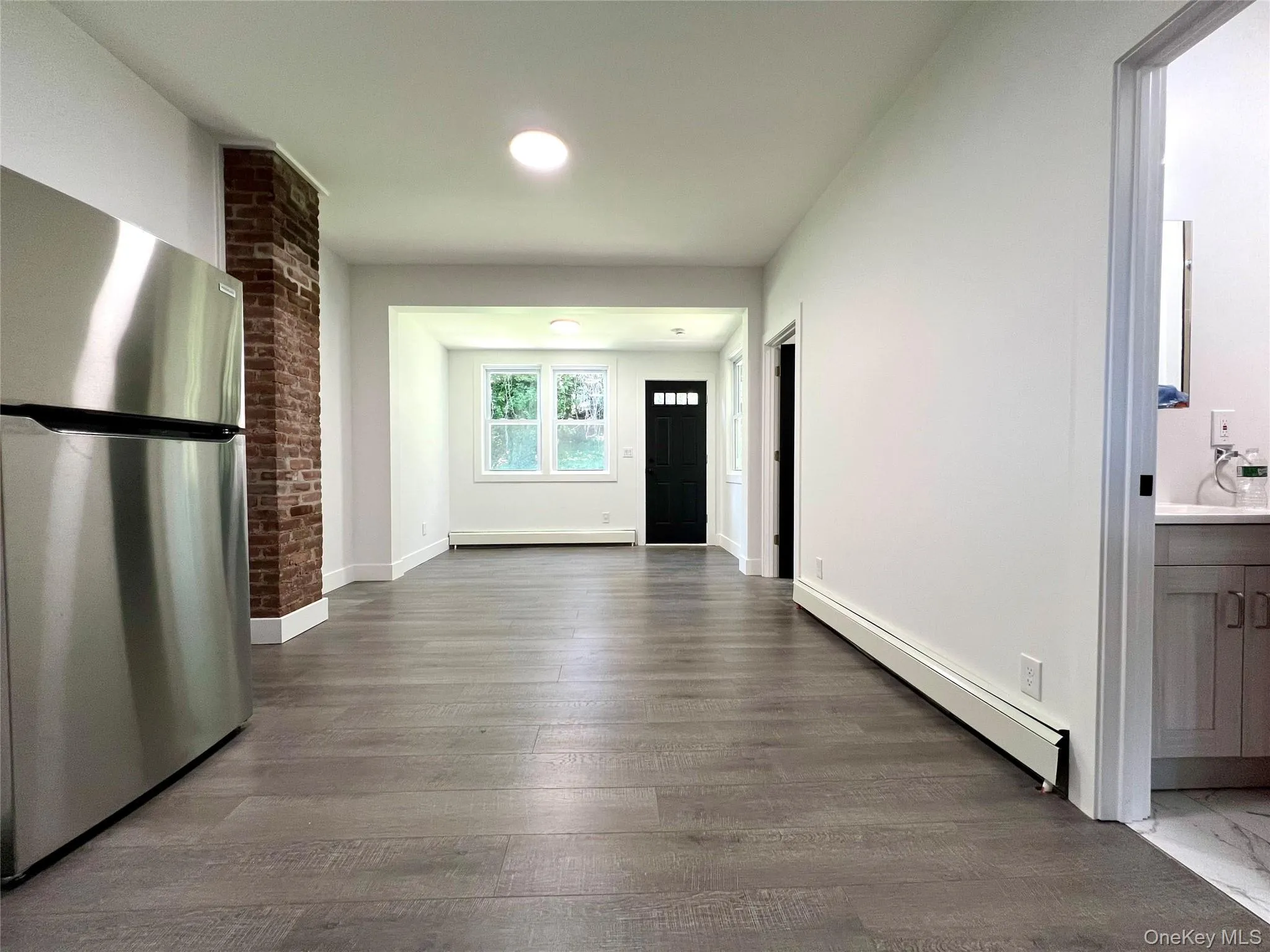 Hallway with a baseboard radiator, wood finished floors, and a baseboard heating unit Hallway with a baseboard radiator, wood finished floors, and a baseboard heating unit