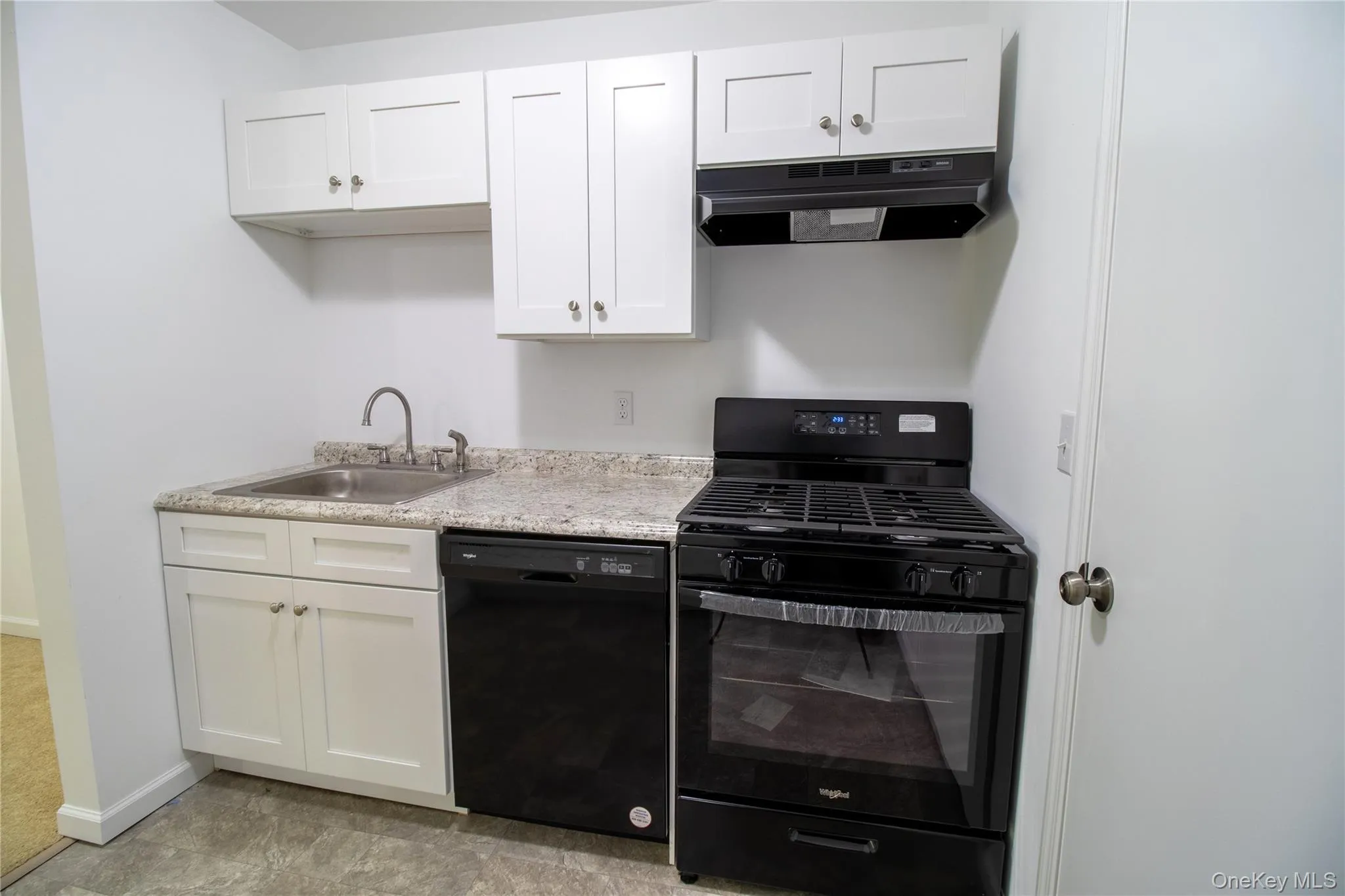 Kitchen featuring black appliances, light countertops, white cabinets, and exhaust hood Kitchen featuring black appliances, light countertops, white cabinets, and exhaust hood