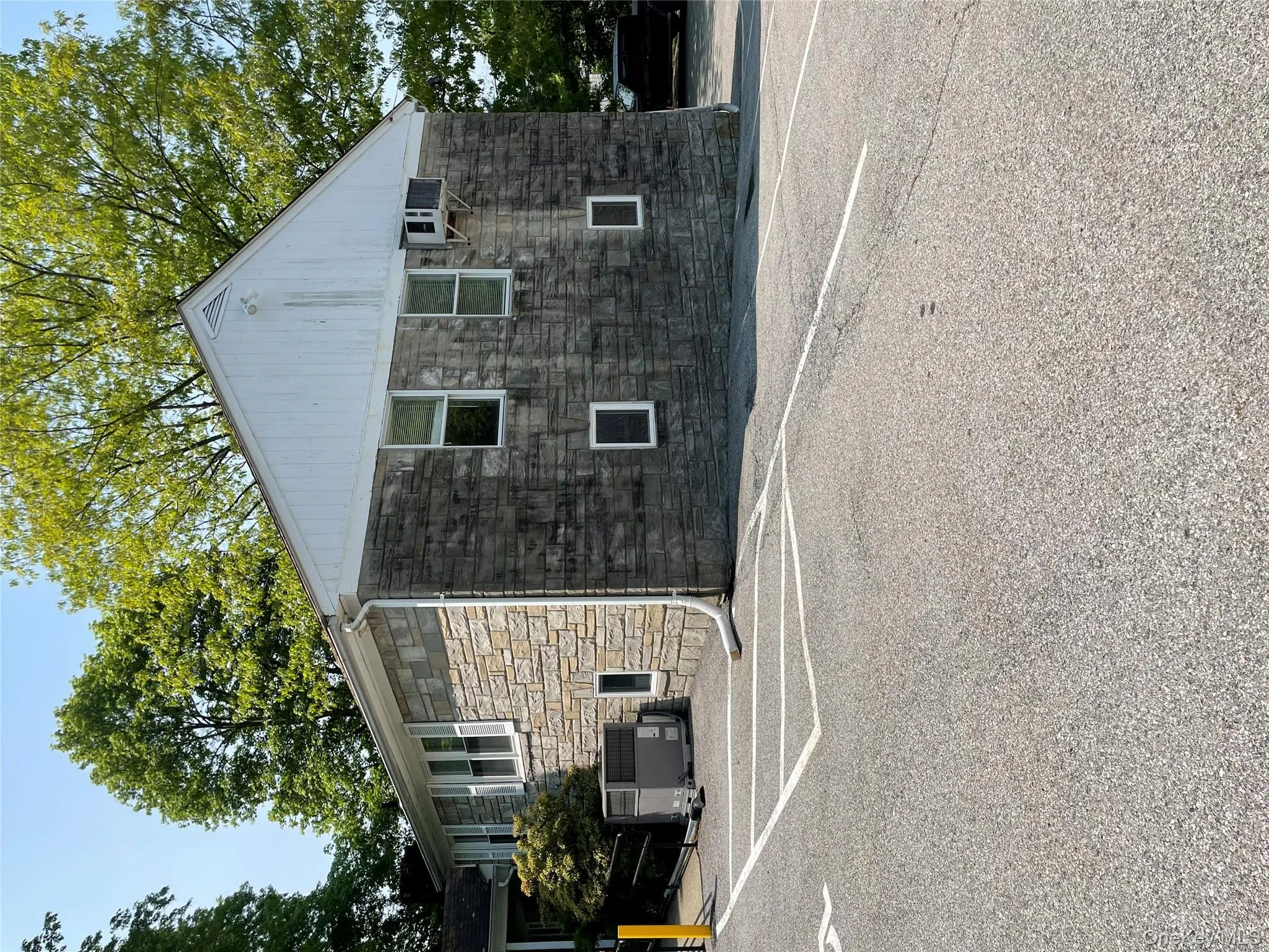 View of property exterior featuring stone siding and uncovered parking View of property exterior featuring stone siding and uncovered parking