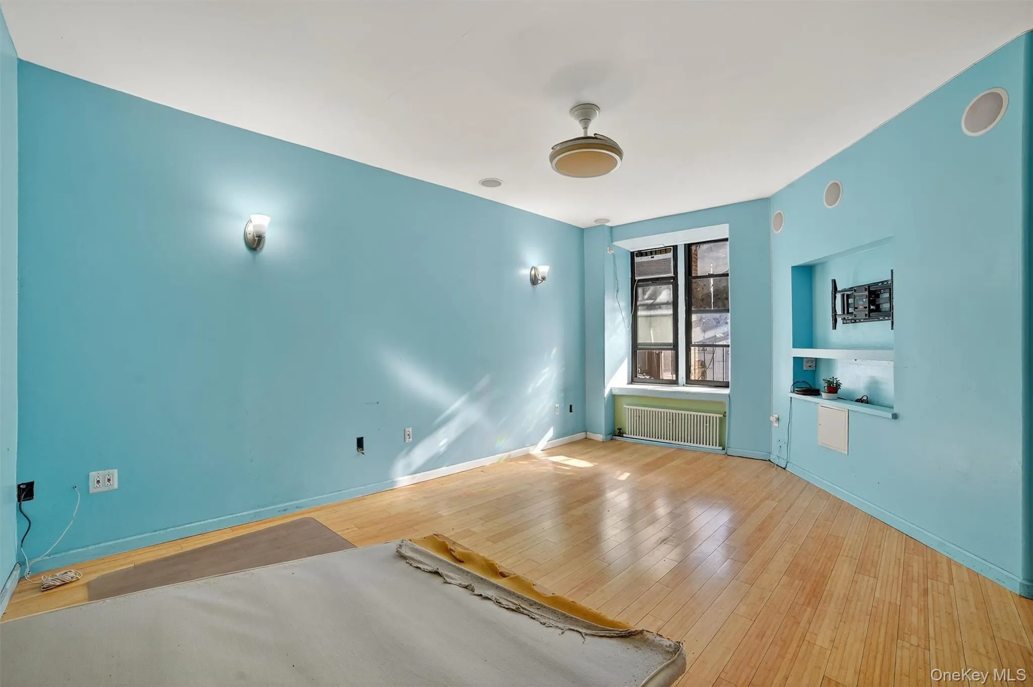Spare room with wood finished floors, radiator heating unit, and built in shelves Spare room with wood finished floors, radiator heating unit, and built in shelves