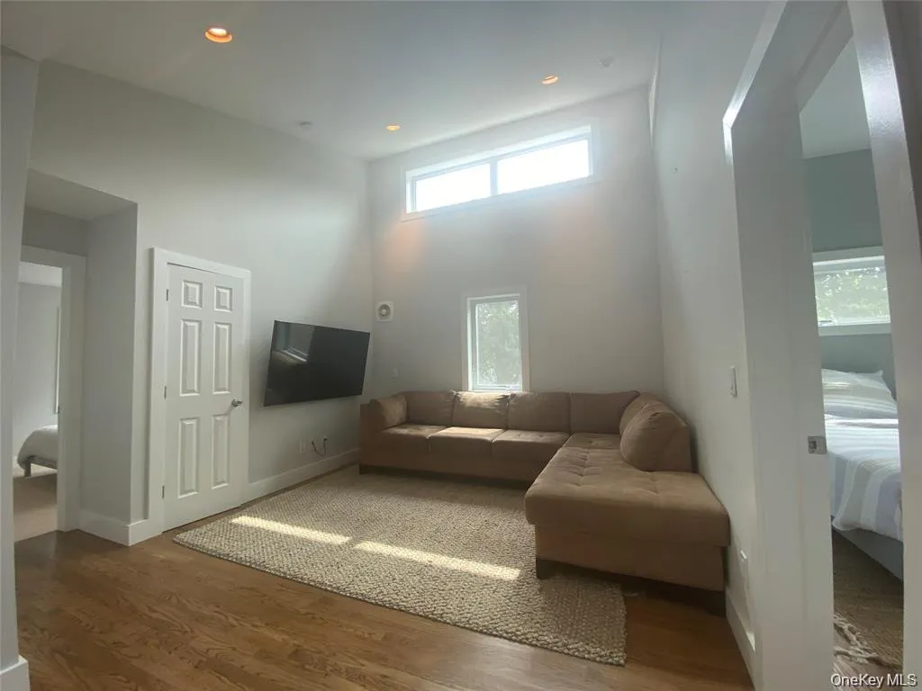 Living room featuring wood finished floors, recessed lighting, and a towering ceiling Living room featuring wood finished floors, recessed lighting, and a towering ceiling