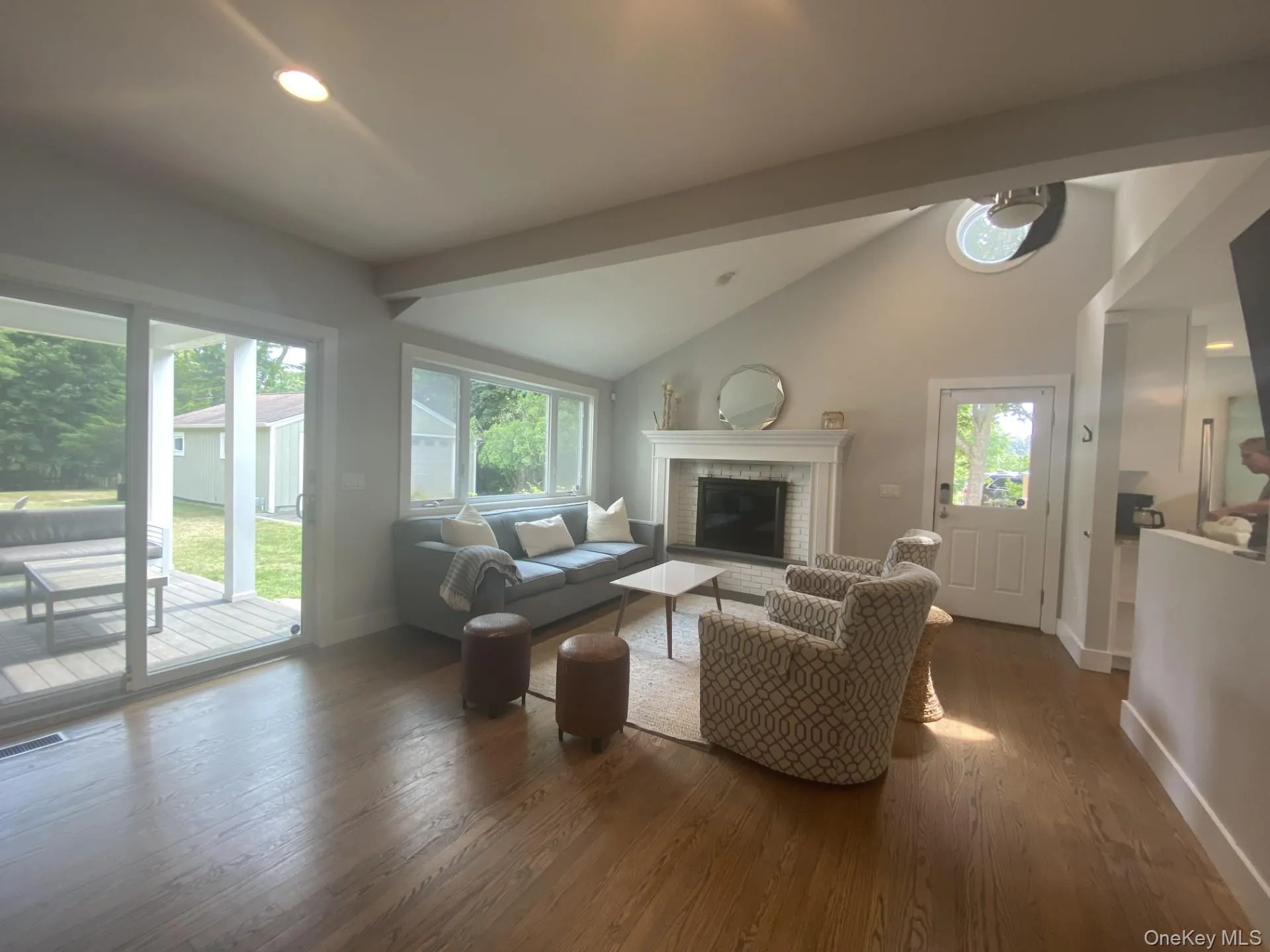 Living area featuring beam ceiling, a brick fireplace, wood finished floors, high vaulted ceiling, and recessed lighting Living area featuring beam ceiling, a brick fireplace, wood finished floors, high vaulted ceiling, and recessed lighting