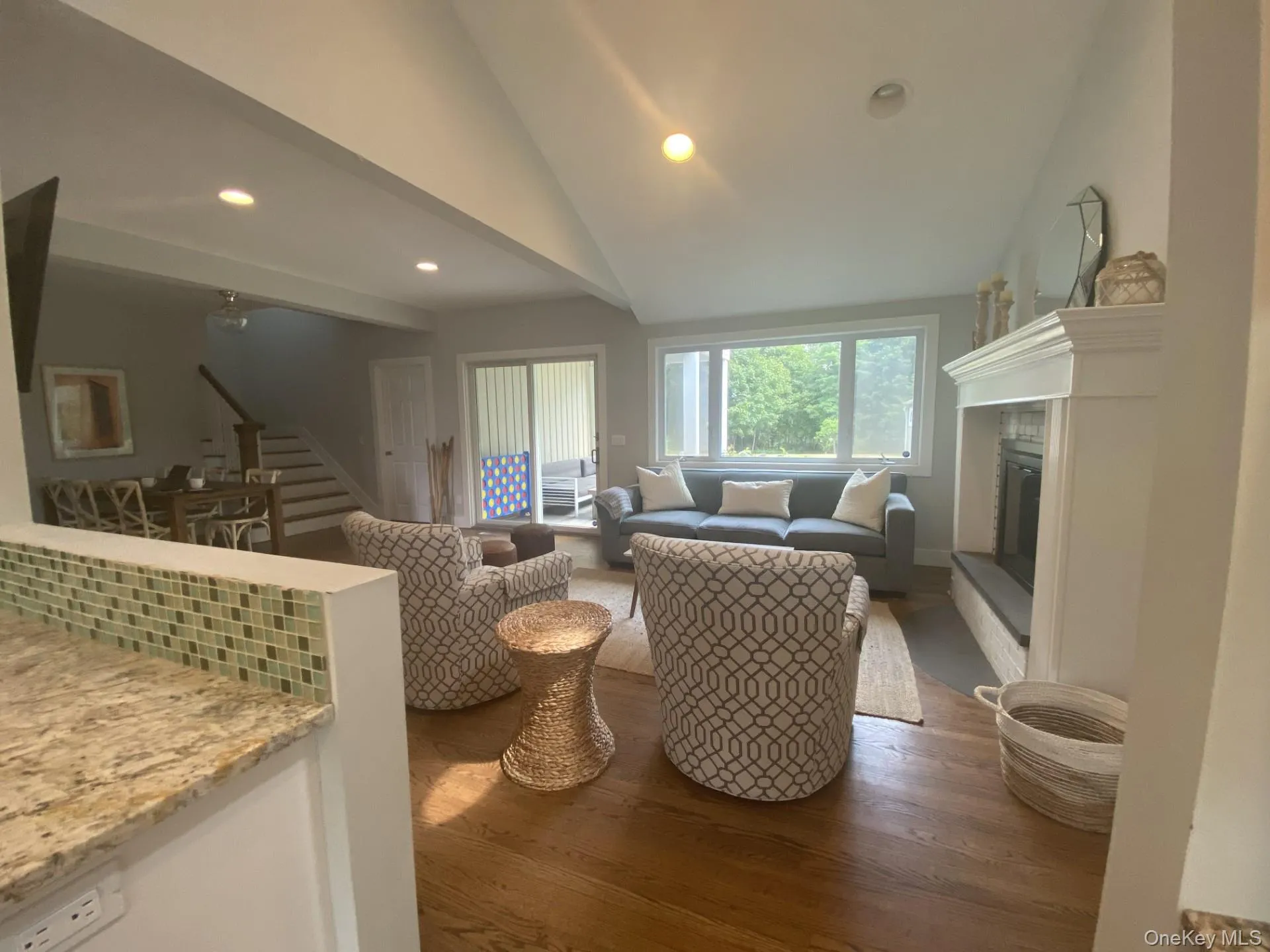 Living area featuring recessed lighting, a glass covered fireplace, wood finished floors, and stairs Living area featuring recessed lighting, a glass covered fireplace, wood finished floors, and stairs