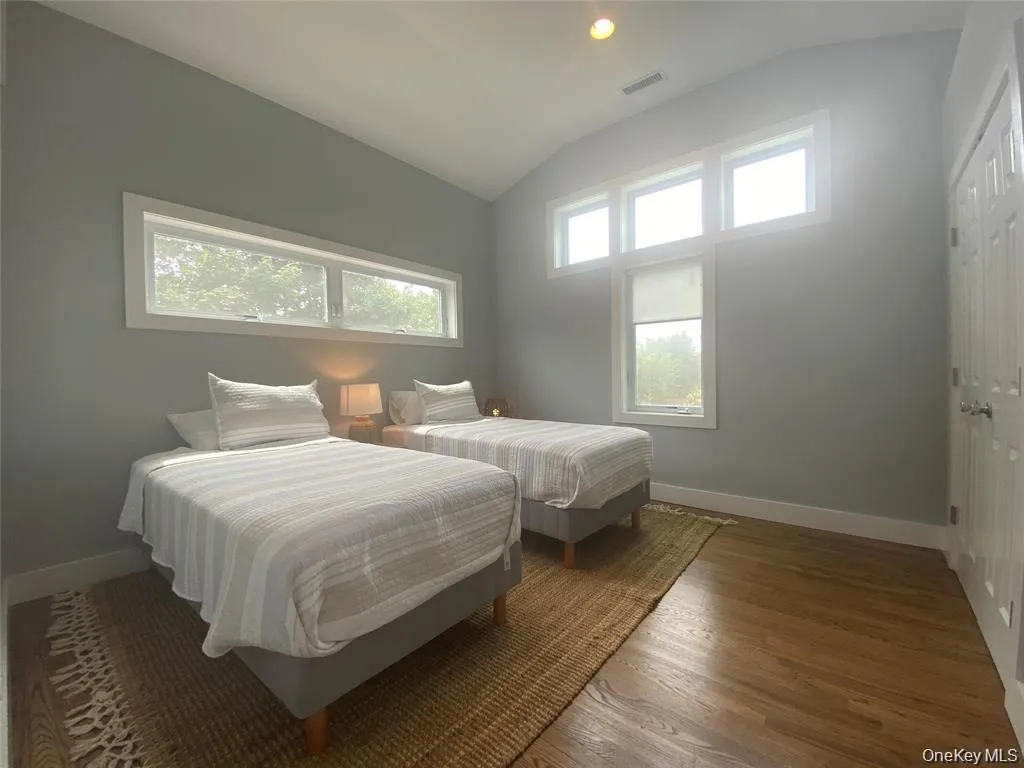 Bedroom with lofted ceiling, multiple windows, wood finished floors, and recessed lighting Bedroom with lofted ceiling, multiple windows, wood finished floors, and recessed lighting