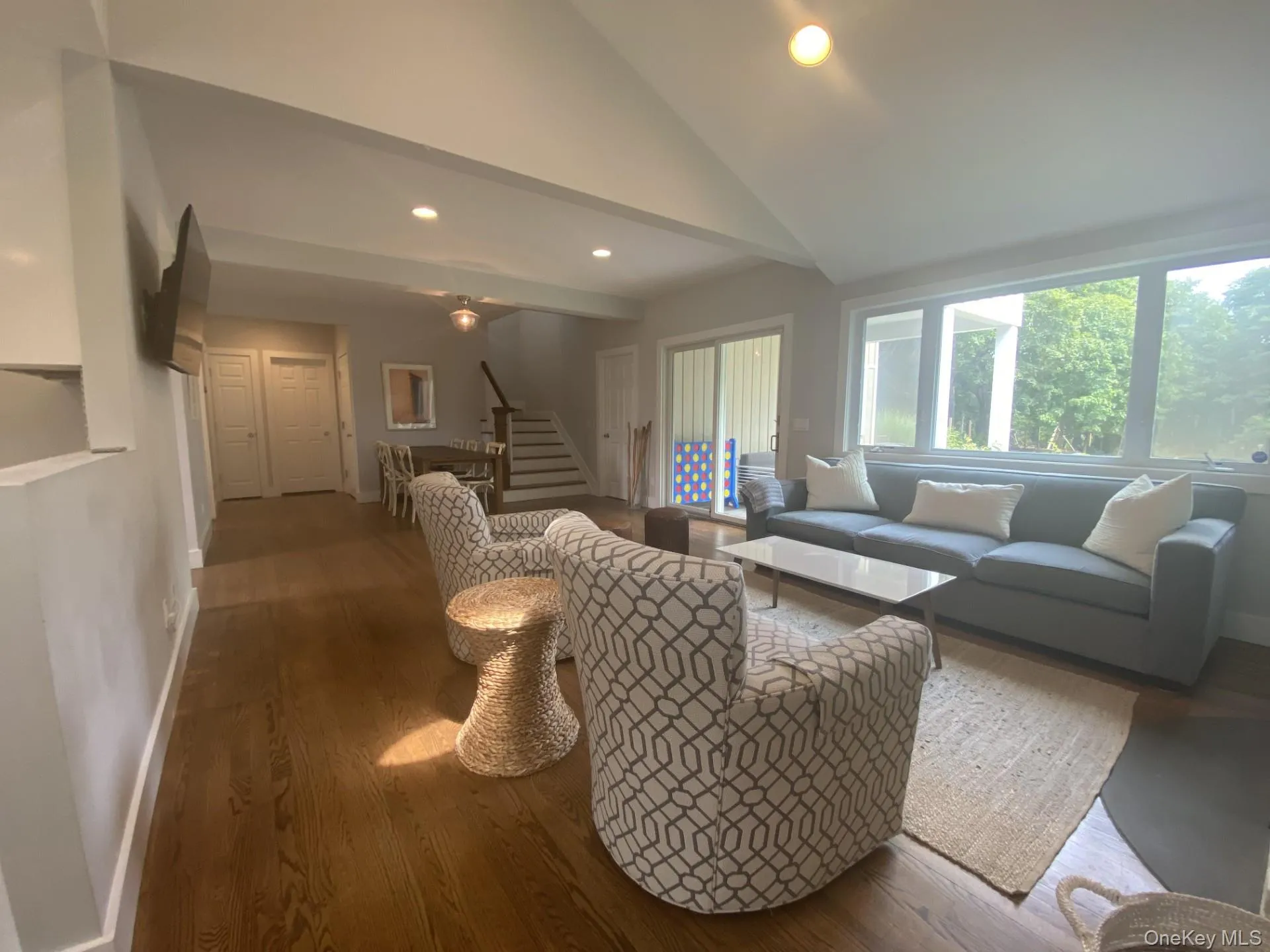 Living room with recessed lighting, lofted ceiling, wood finished floors, and stairs Living room with recessed lighting, lofted ceiling, wood finished floors, and stairs