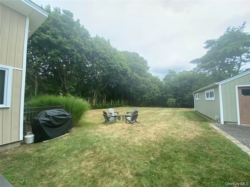 View of grassy yard with an outbuilding, view of scattered trees, and a fire pit View of grassy yard with an outbuilding, view of scattered trees, and a fire pit