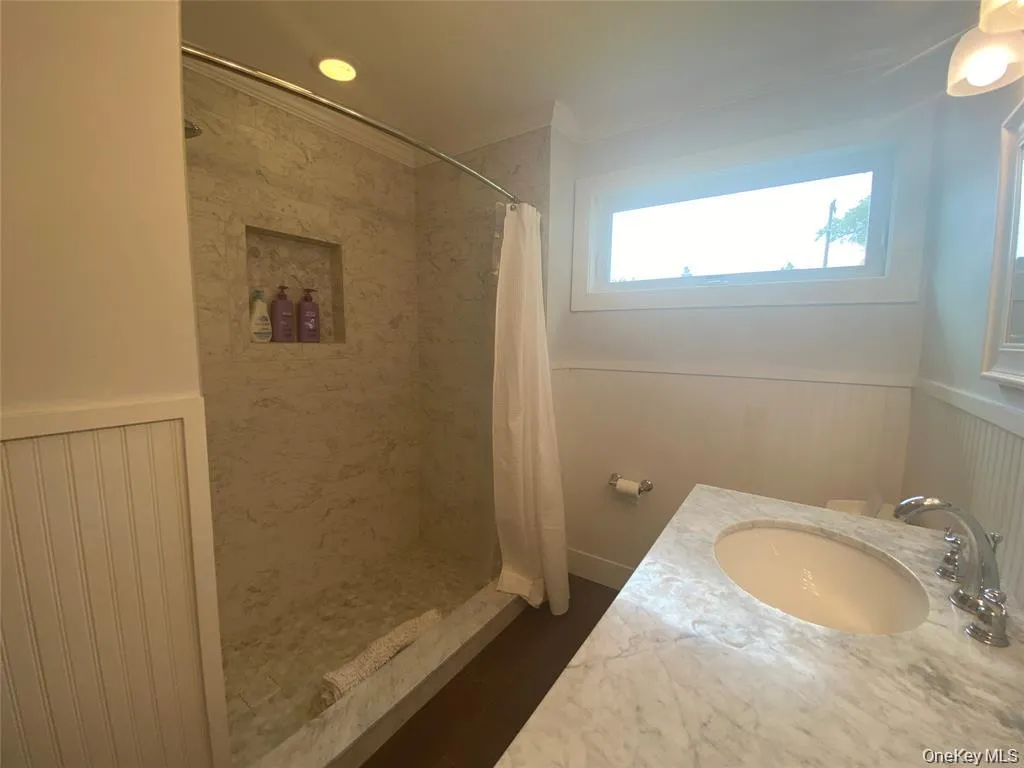 Full bath featuring wainscoting, a shower stall, ornamental molding, and vanity Full bath featuring wainscoting, a shower stall, ornamental molding, and vanity
