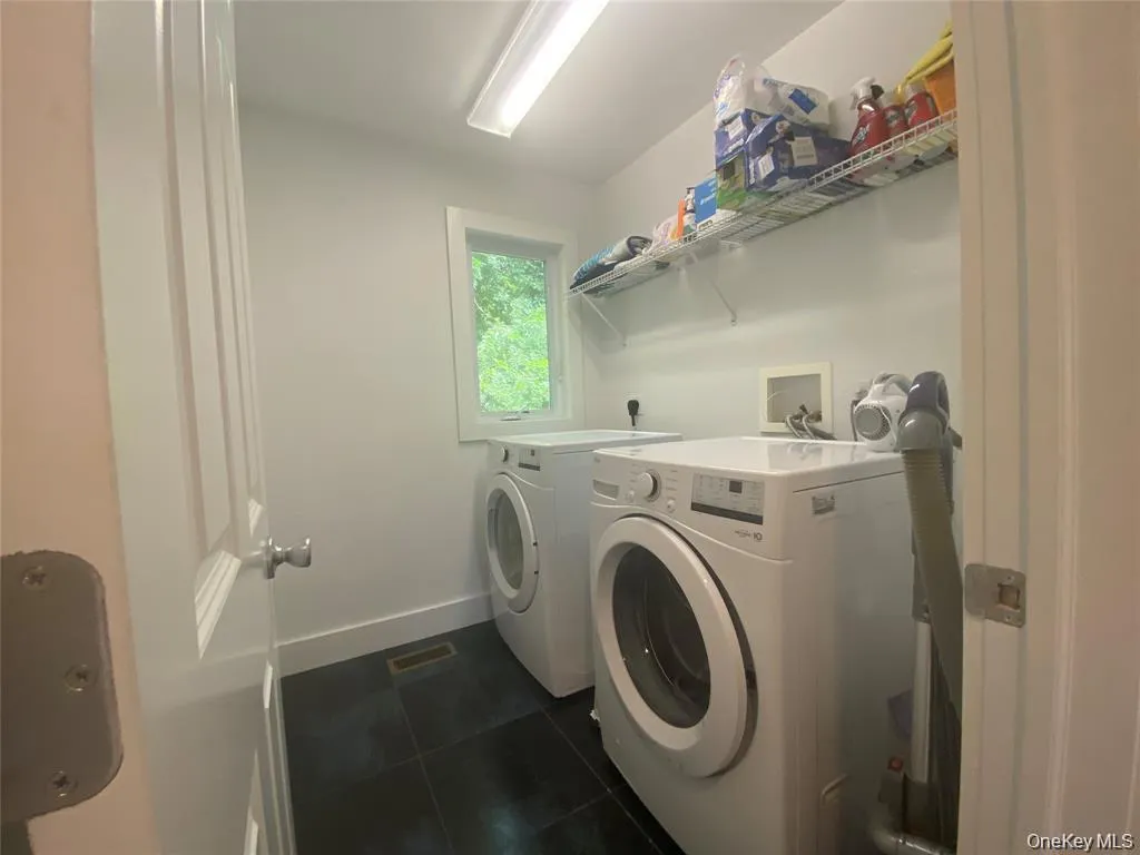 Laundry area featuring dark tile patterned floors and independent washer and dryer Laundry area featuring dark tile patterned floors and independent washer and dryer