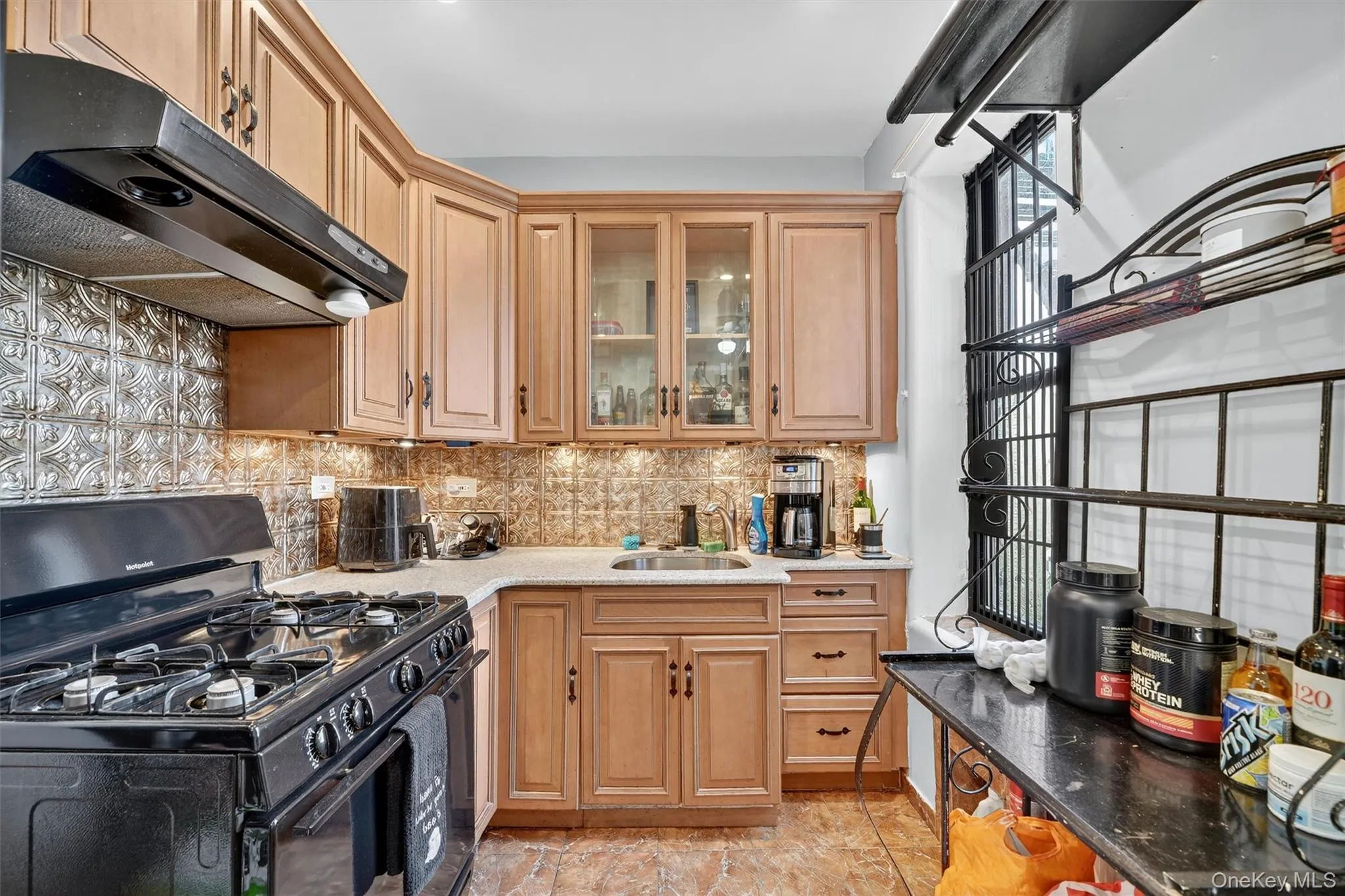 Kitchen with gas stove, decorative backsplash, dark stone countertops, under cabinet range hood, and glass insert cabinets Kitchen with gas stove, decorative backsplash, dark stone countertops, under cabinet range hood, and glass insert cabinets