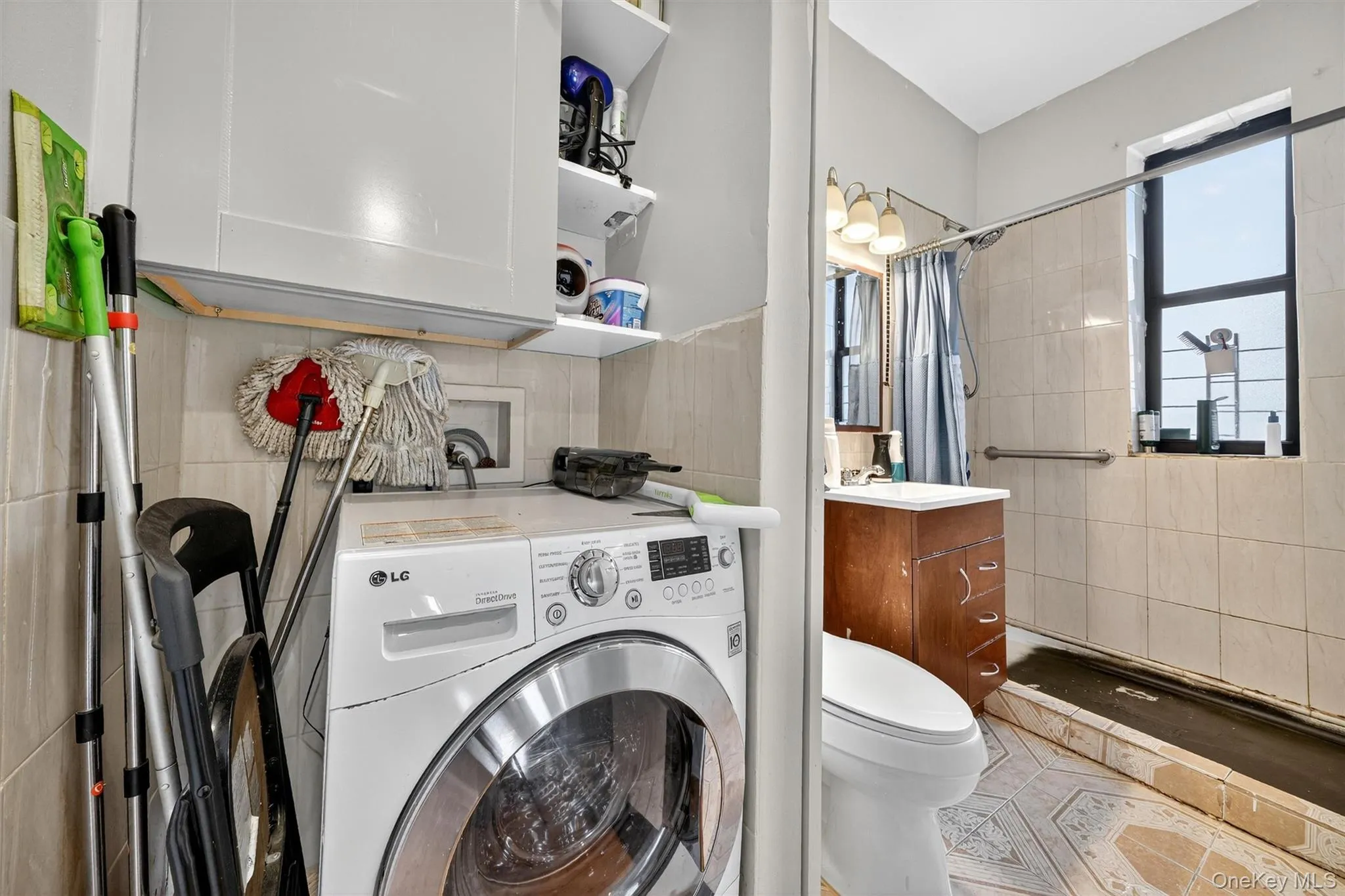 Laundry area featuring washer / dryer, tile walls, and light tile patterned floors Laundry area featuring washer / dryer, tile walls, and light tile patterned floors