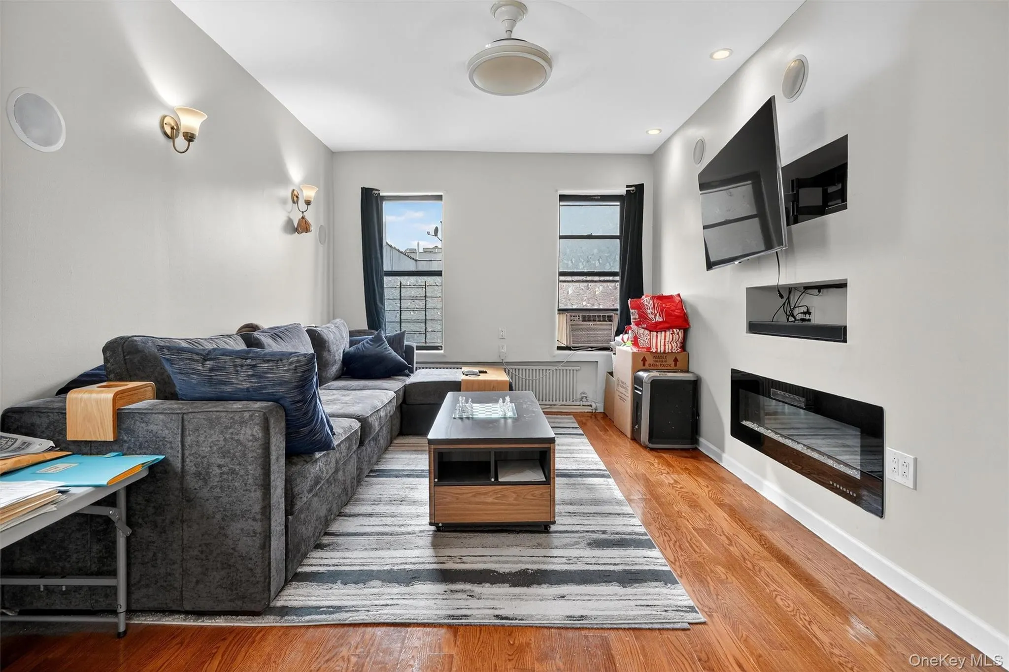 Living room featuring light wood-style floors, recessed lighting, radiator heating unit, and a glass covered fireplace Living room featuring light wood-style floors, recessed lighting, radiator heating unit, and a glass covered fireplace