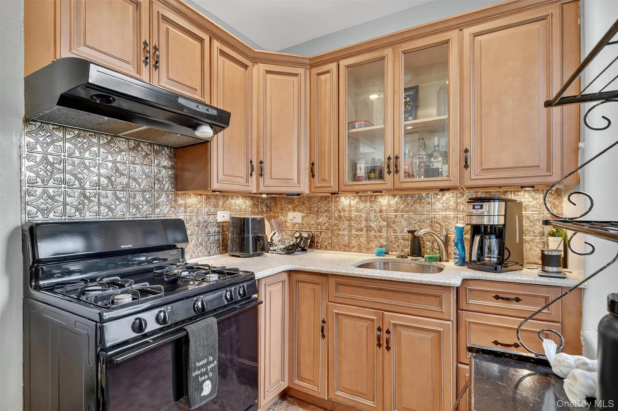 Kitchen with gas stove, under cabinet range hood, tasteful backsplash, light stone countertops, and glass insert cabinets Kitchen with gas stove, under cabinet range hood, tasteful backsplash, light stone countertops, and glass insert cabinets