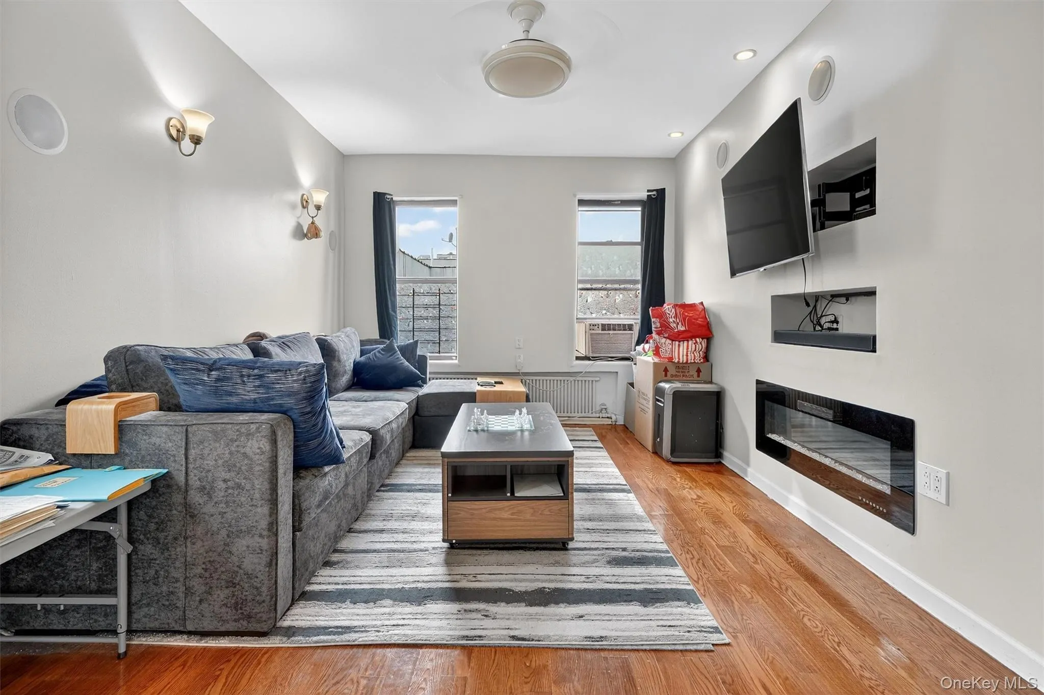 Living room featuring light wood-style floors, radiator, a glass covered fireplace, and recessed lighting Living room featuring light wood-style floors, radiator, a glass covered fireplace, and recessed lighting