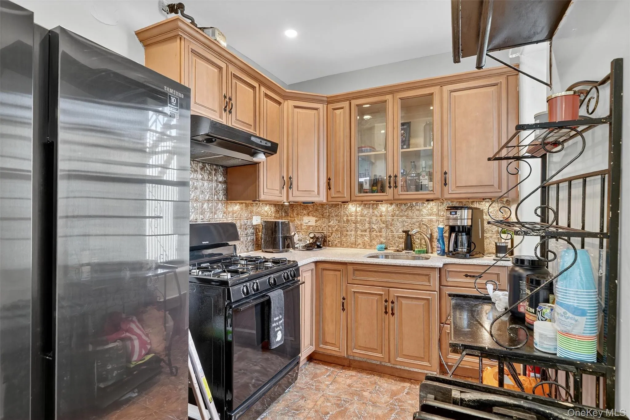 Kitchen with freestanding refrigerator, gas stove, backsplash, and under cabinet range hood Kitchen with freestanding refrigerator, gas stove, backsplash, and under cabinet range hood