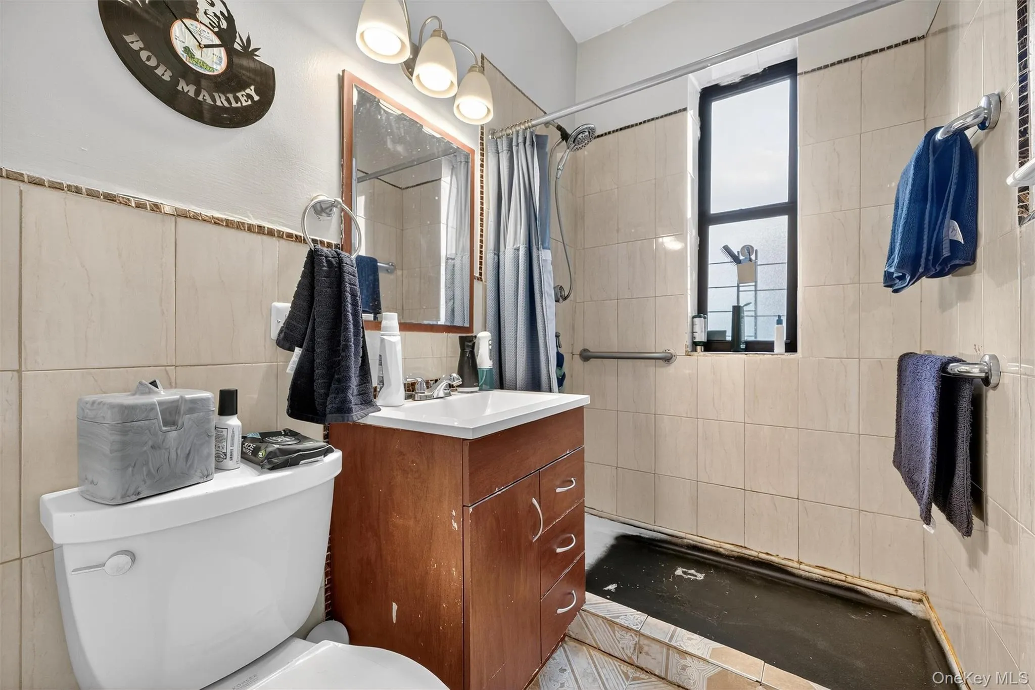 Full bathroom with tile walls, a tile shower, and vanity Full bathroom with tile walls, a tile shower, and vanity