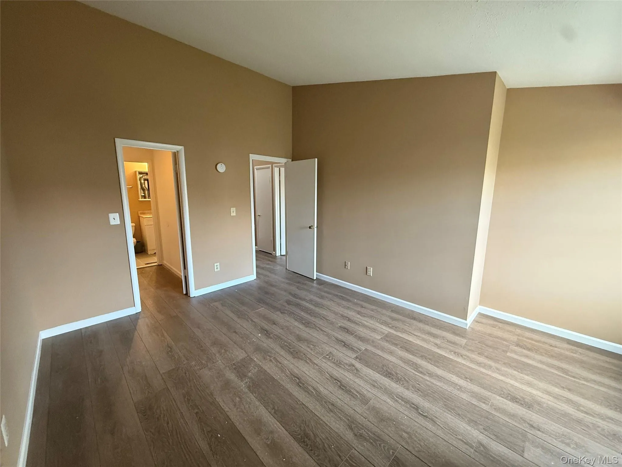 Unfurnished bedroom with wood finished floors and a high ceiling Unfurnished bedroom with wood finished floors and a high ceiling