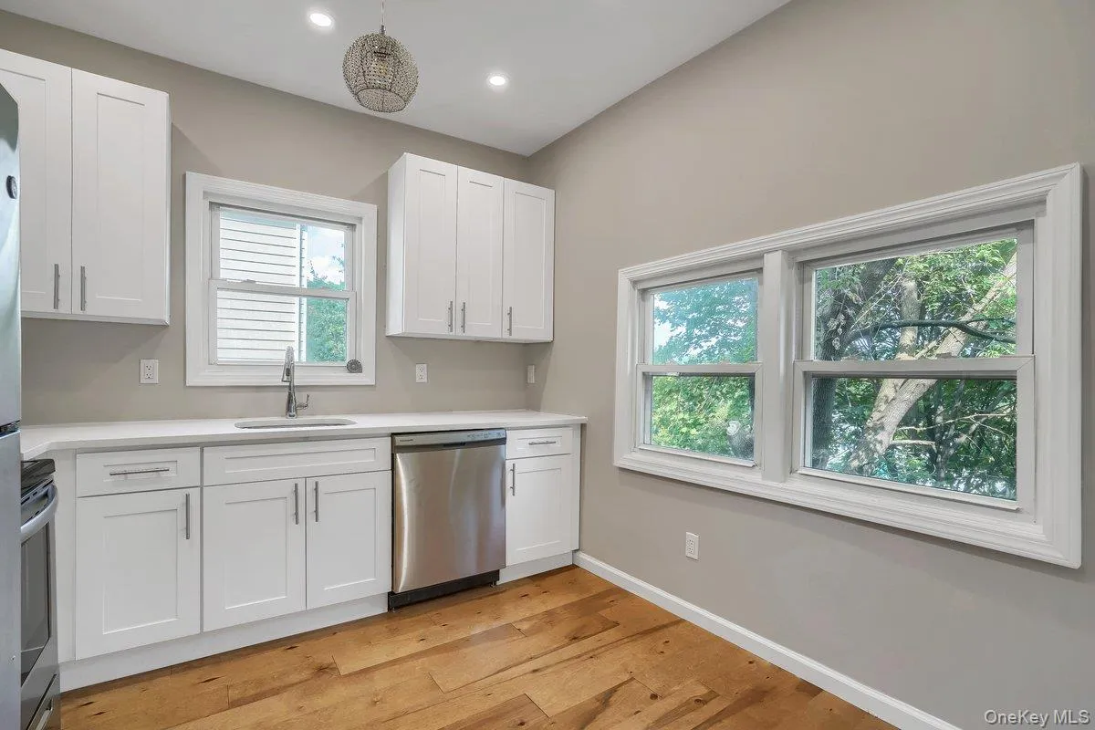 Kitchen with white cabinetry, appliances with stainless steel finishes, light wood-type flooring, recessed lighting, and decorative light fixtures Kitchen with white cabinetry, appliances with stainless steel finishes, light wood-type flooring, recessed lighting, and decorative light fixtures