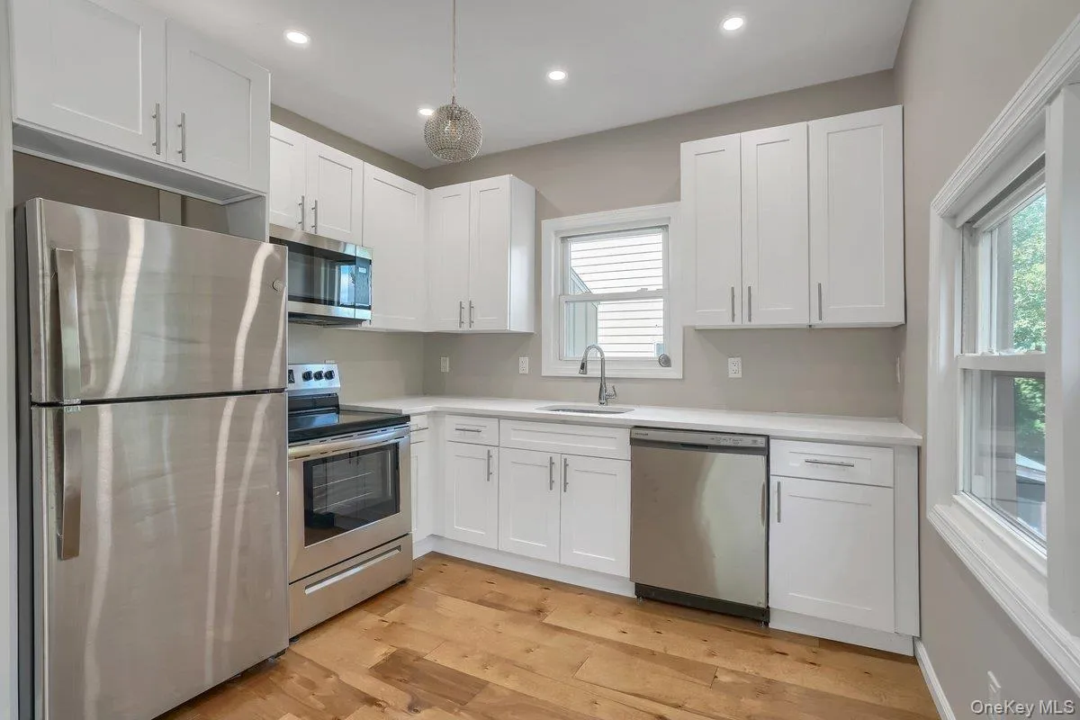 Kitchen with appliances with stainless steel finishes, white cabinets, light wood-style floors, recessed lighting, and pendant lighting Kitchen with appliances with stainless steel finishes, white cabinets, light wood-style floors, recessed lighting, and pendant lighting