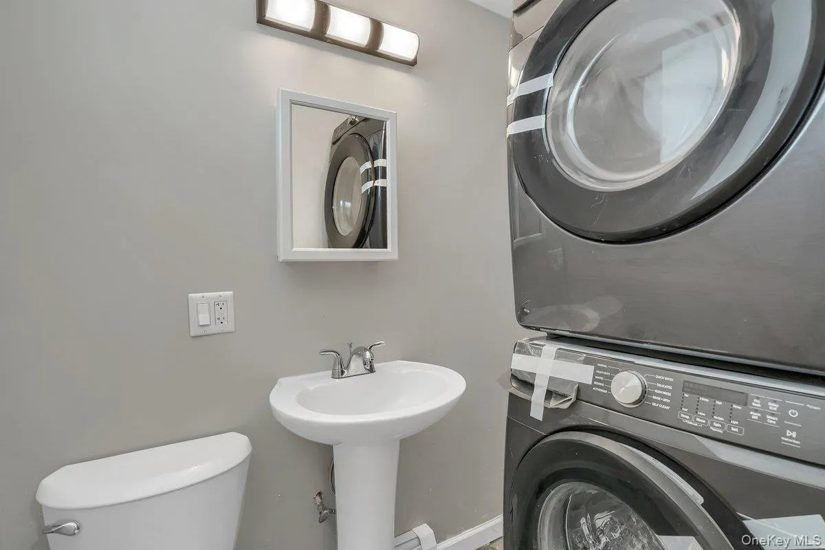 Bathroom with toilet and stacked washer / drying machine Bathroom with toilet and stacked washer / drying machine