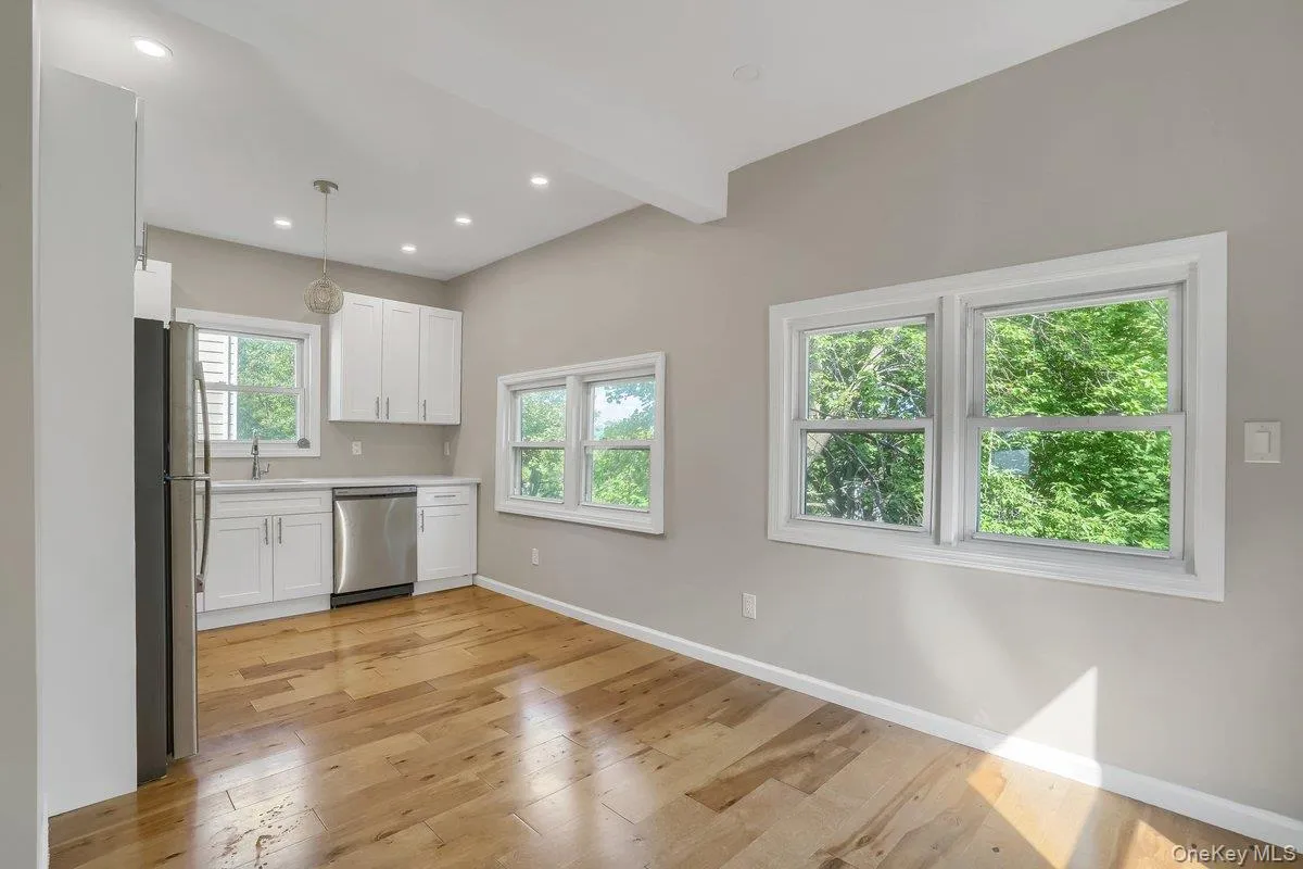 Kitchen with white cabinetry, light wood-style flooring, appliances with stainless steel finishes, pendant lighting, and beamed ceiling Kitchen with white cabinetry, light wood-style flooring, appliances with stainless steel finishes, pendant lighting, and beamed ceiling