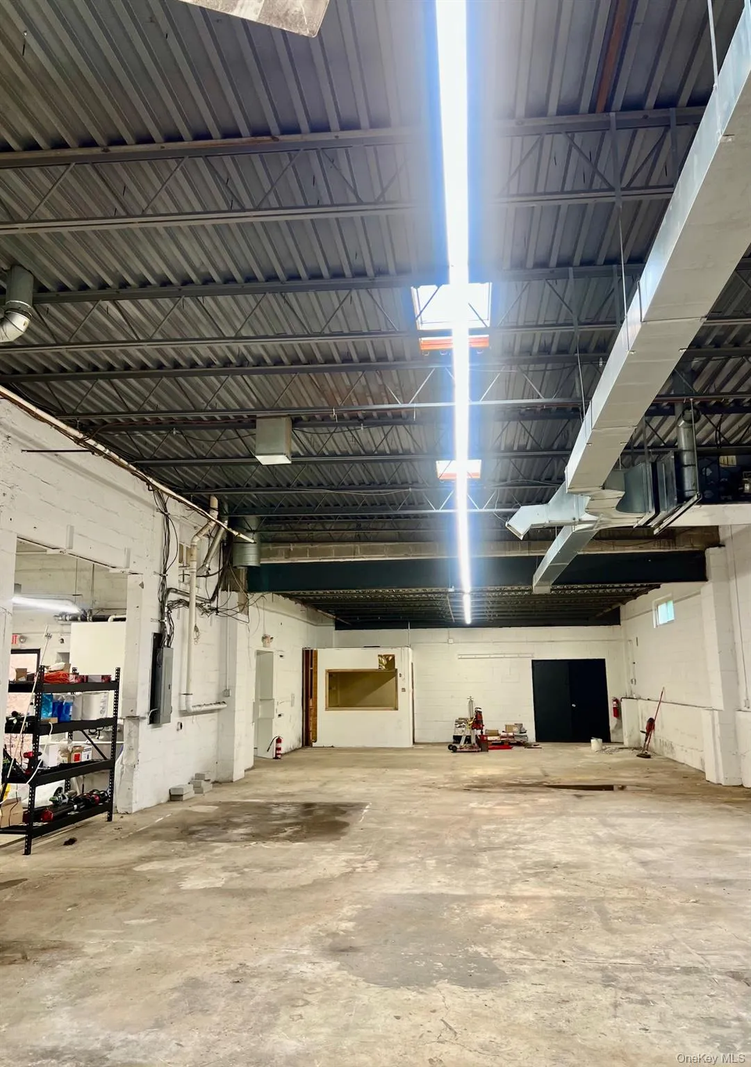 Misc room featuring concrete flooring, concrete block wall, and a garage Misc room featuring concrete flooring, concrete block wall, and a garage