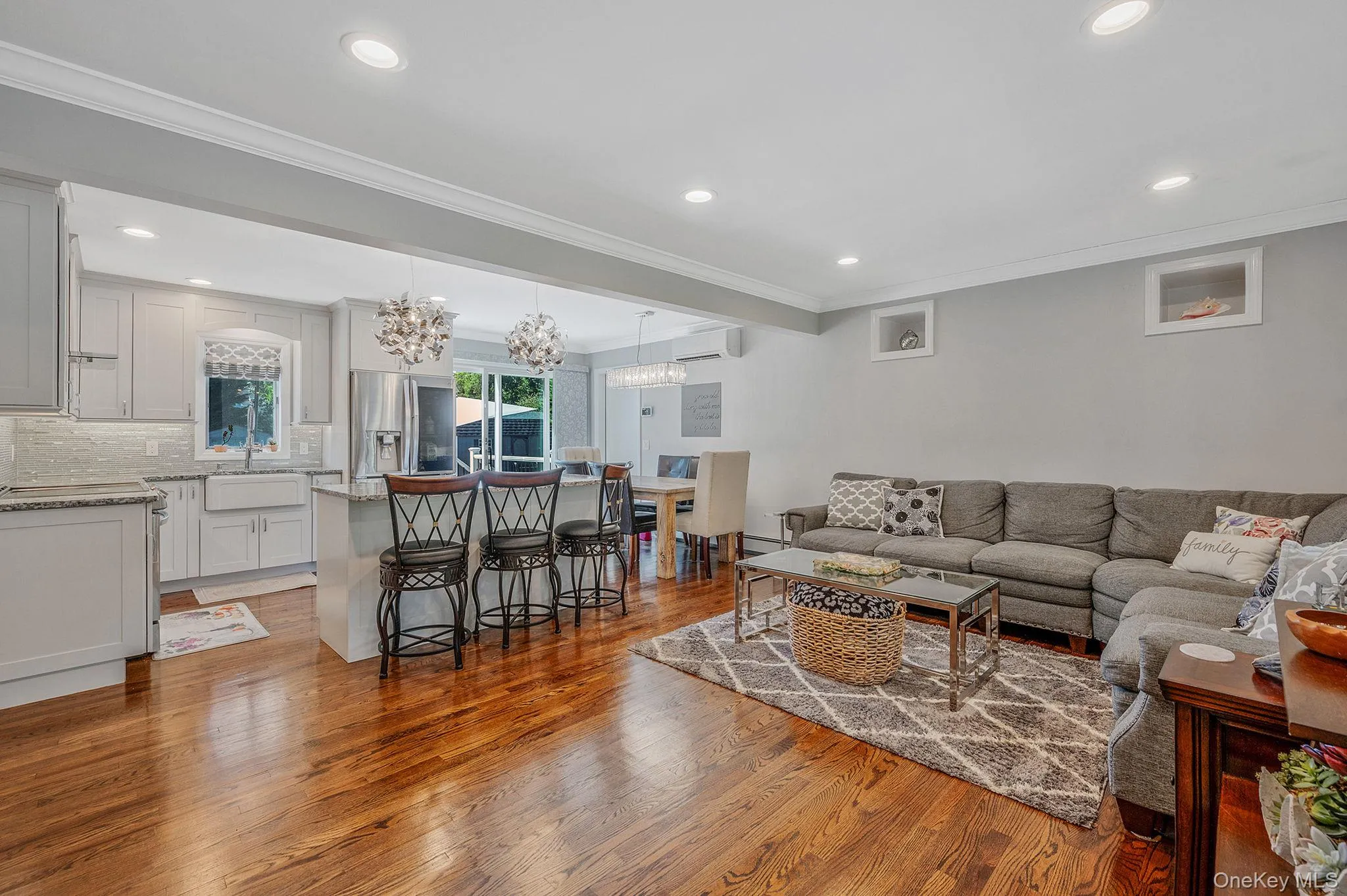 Living room featuring ornamental molding, light wood-style floors, recessed lighting, a chandelier, and a wall mounted air conditioner Living room featuring ornamental molding, light wood-style floors, recessed lighting, a chandelier, and a wall mounted air conditioner