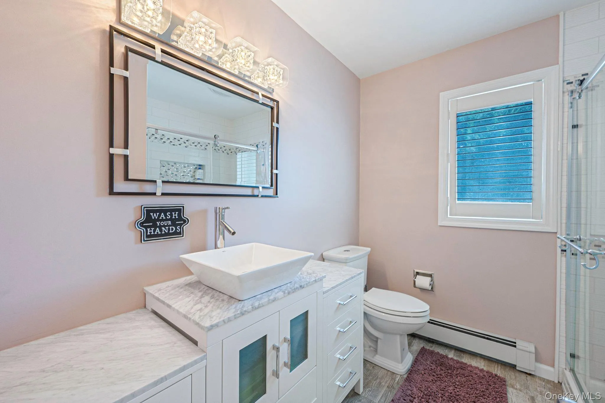 Bathroom featuring a baseboard radiator, vanity, a shower stall, and wood finished floors Bathroom featuring a baseboard radiator, vanity, a shower stall, and wood finished floors