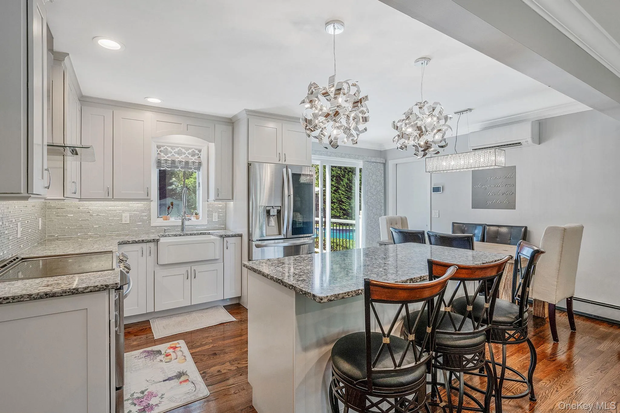 Kitchen featuring appliances with stainless steel finishes, a breakfast bar area, dark wood-type flooring, tasteful backsplash, and pendant lighting Kitchen featuring appliances with stainless steel finishes, a breakfast bar area, dark wood-type flooring, tasteful backsplash, and pendant lighting